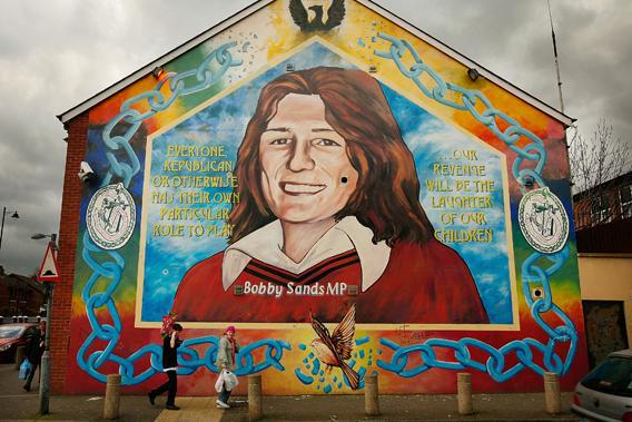 A couple walk past a mural depicting Bobby Sands, who died following a hunger strike in prison, in Belfast, Northern Ireland.