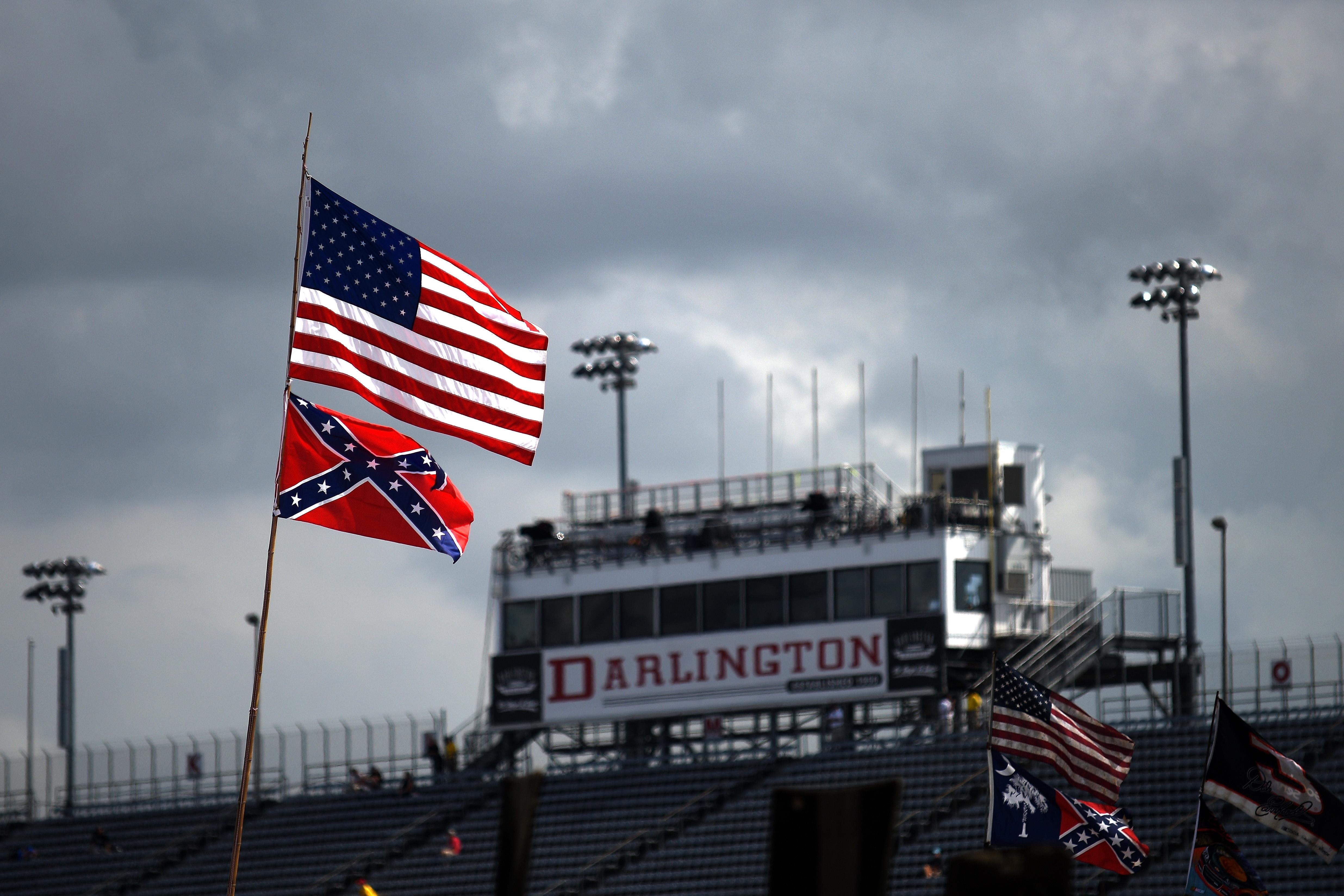 American and Confederate flags are seen flying over a stadium that features a large Darlington sign.