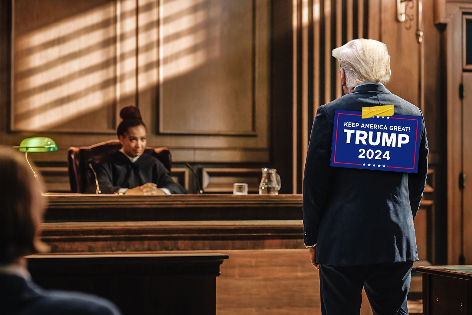 A photo illustration of Donald Trump standing in a courtroom, facing a judge, with a Trump 2024 campaign sign taped to his back.