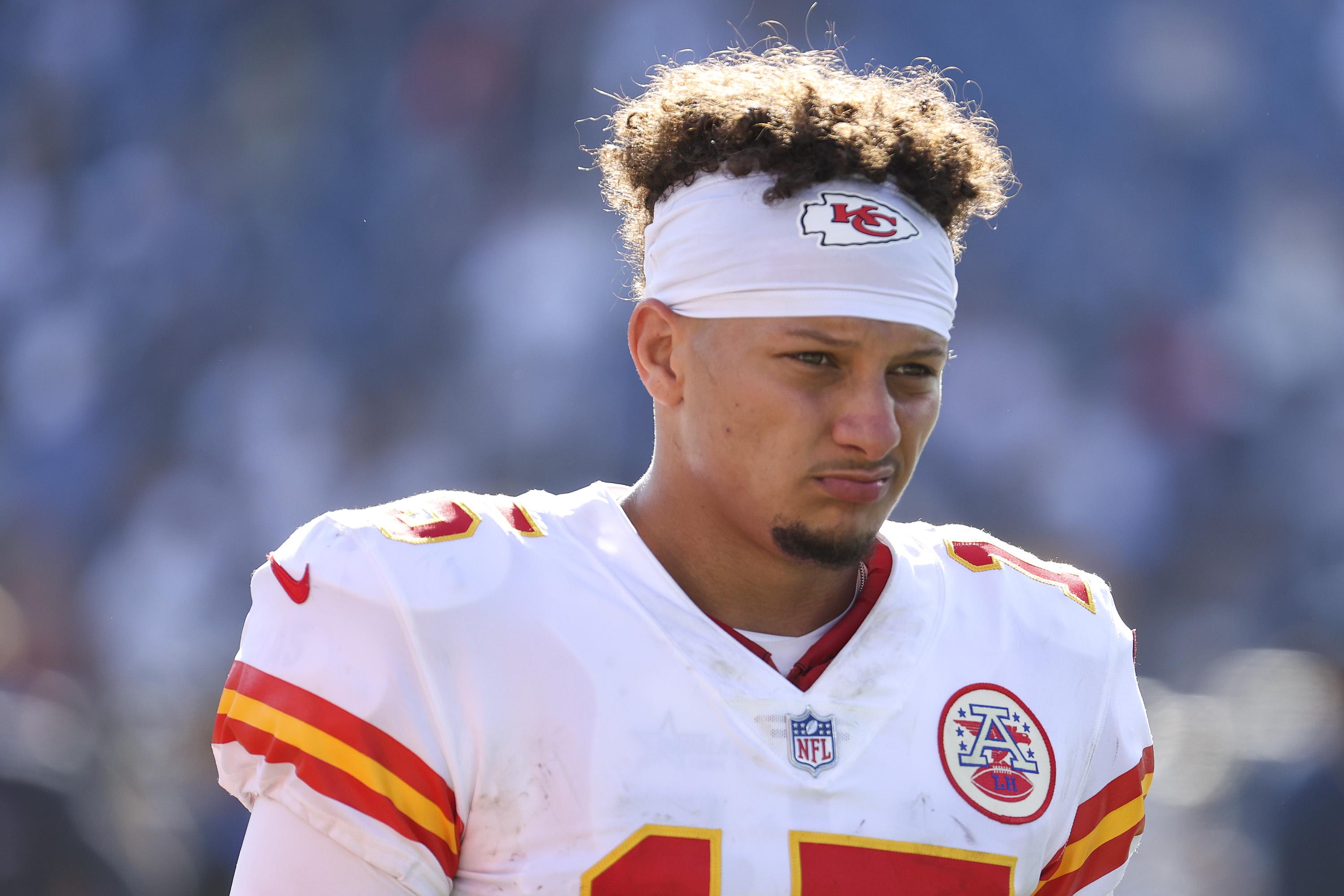 Mahomes in pads and uniform with his helmet off making a "not impressed"–style disappointed expression.