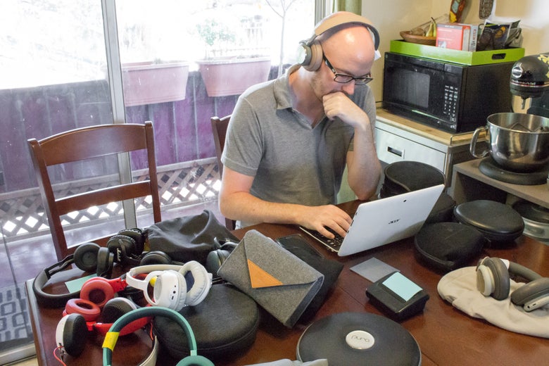 man working at his desk with a pile of headphones