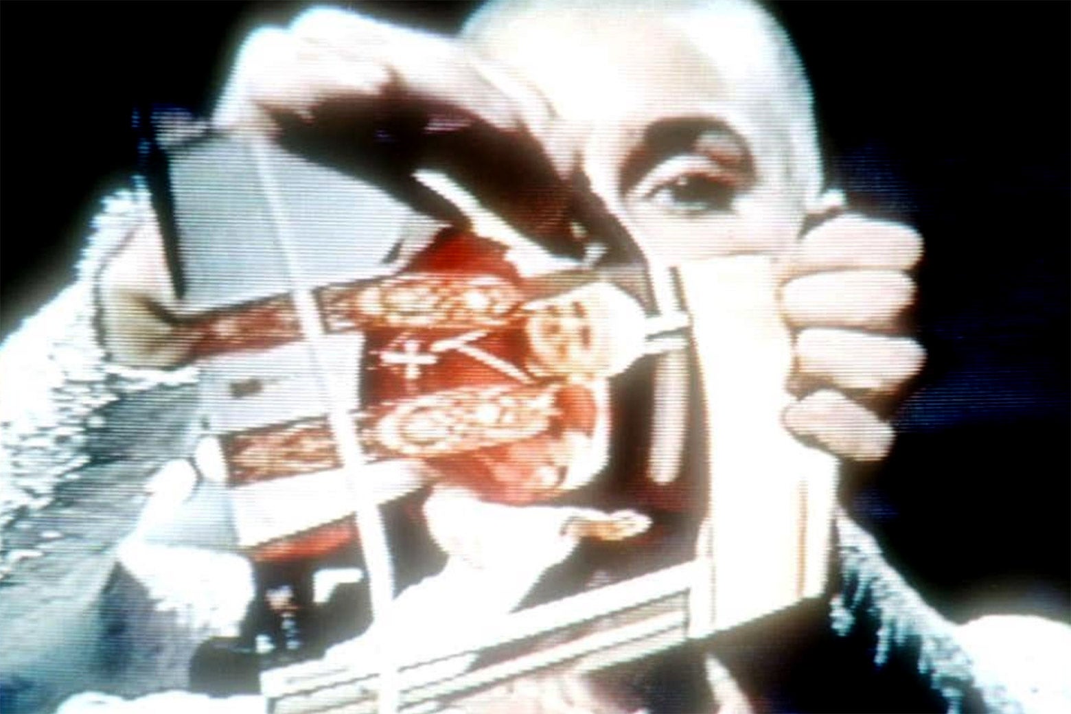 A woman with a shaved head rips up a photo of Pope John Paul II.