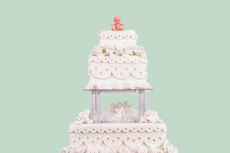 The top of a tiered white wedding cake with a baby as the topper