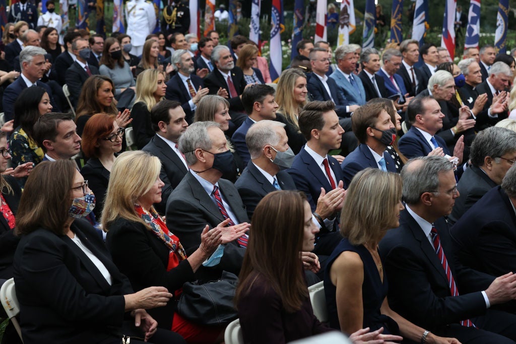 Rows of attendees, mostly maskless, seated closely together in the Rose Garden.