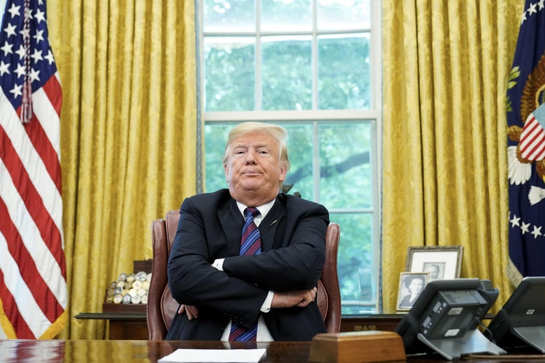 President Trump crosses arms sitting behind the desk in the Oval Office on August 27, 2018. 