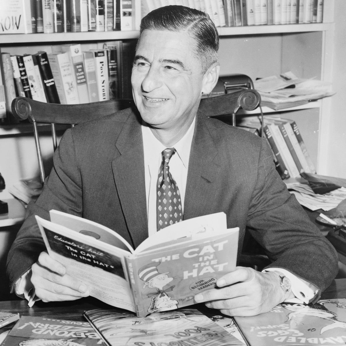 Geisel in his 50s smiling and holding a copy of The Cat in the Hat.