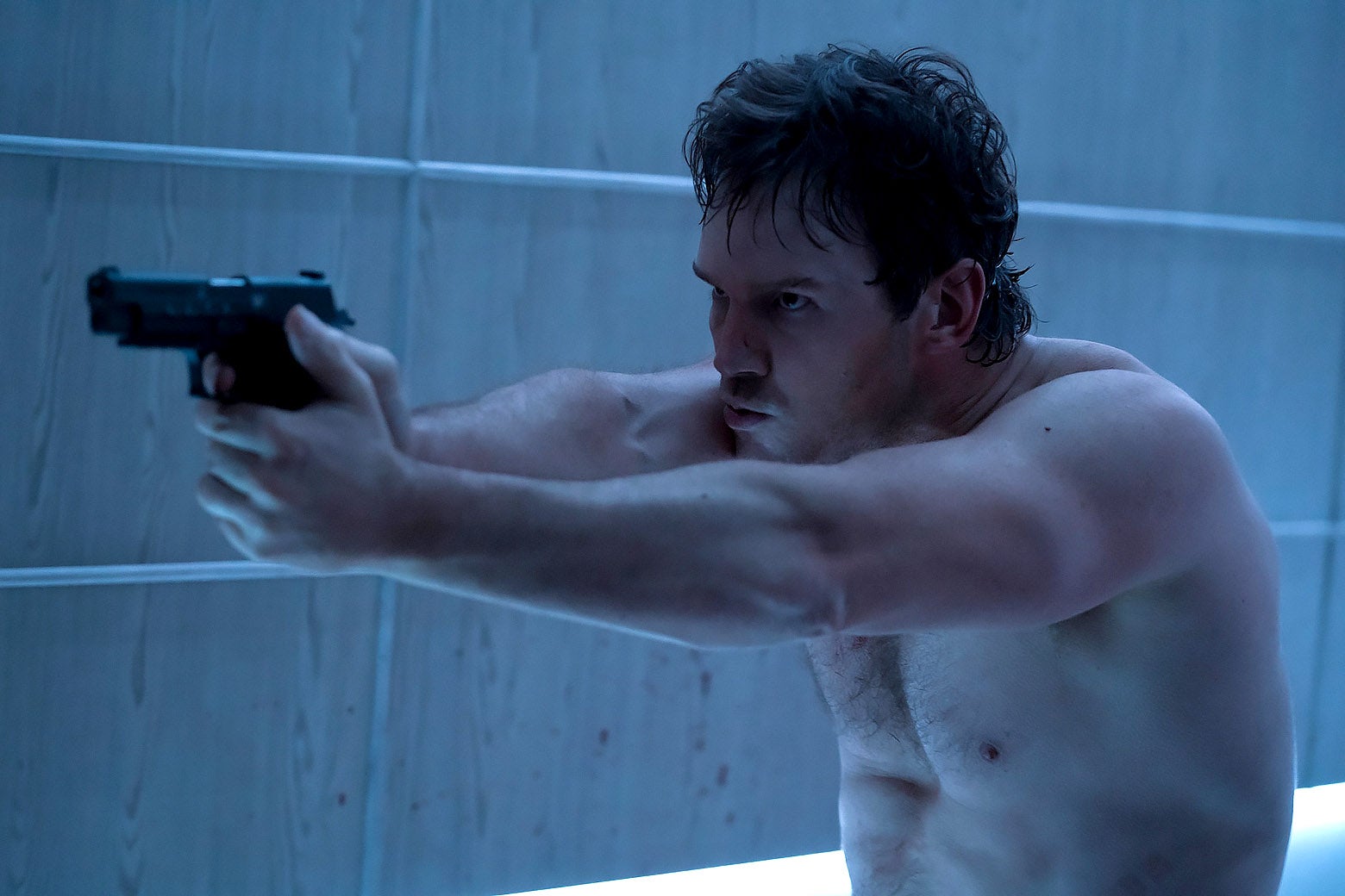A shirtless Chris Pratt points a gun.
