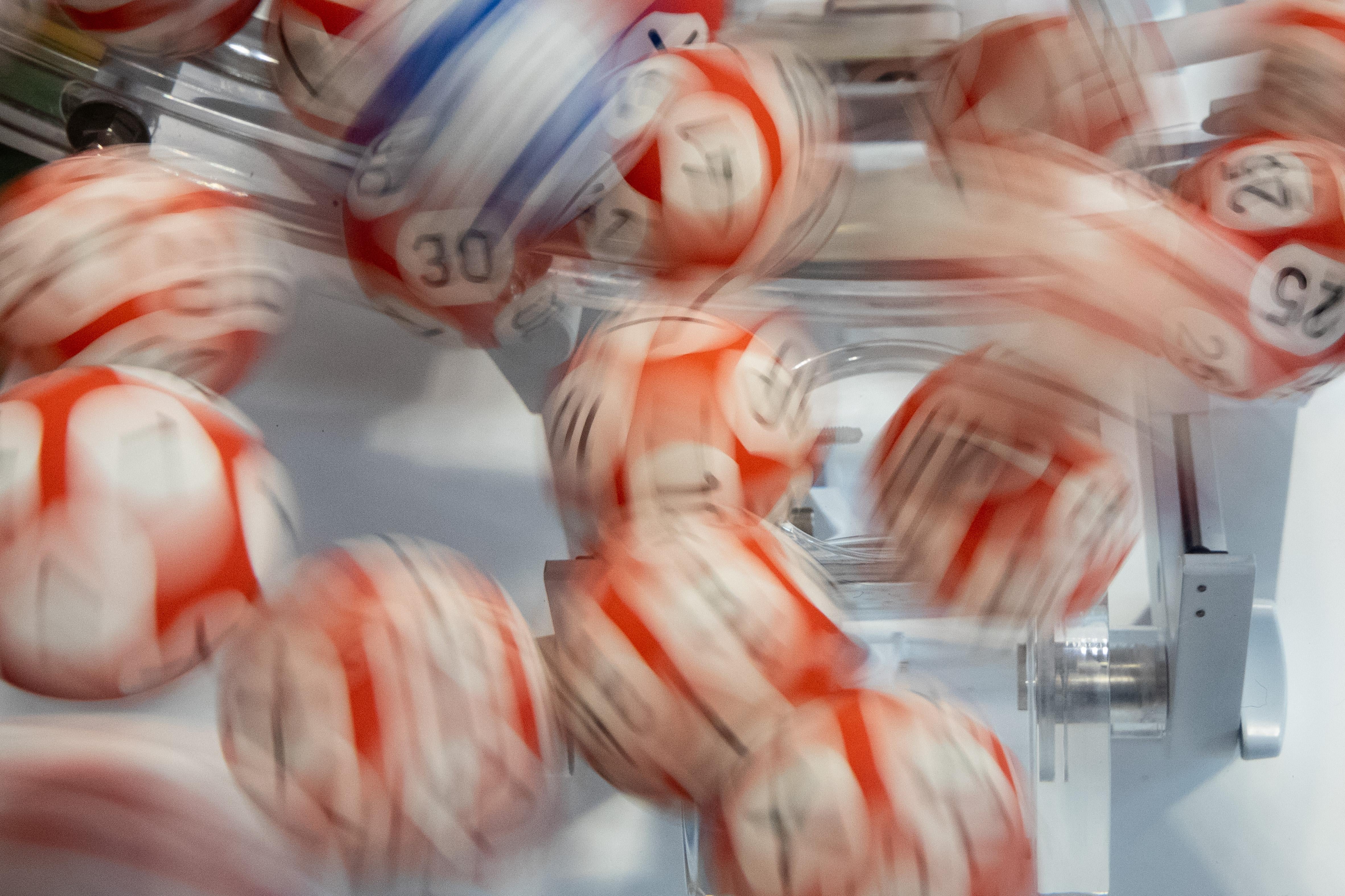 A close-up, blurry photo of numbered lottery balls in motion before being drawn.