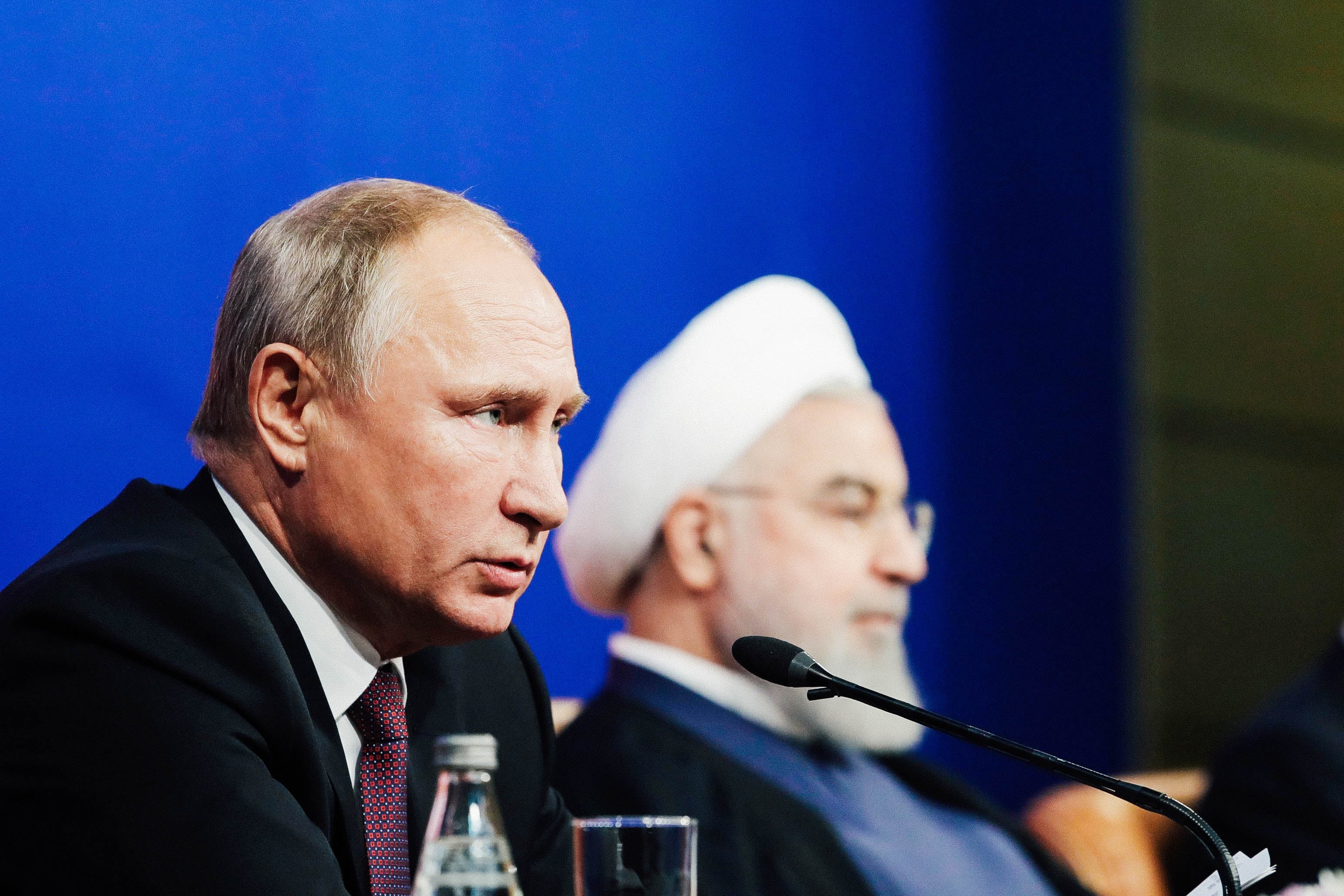 Vladimer Putin talking into a mic at a press table with Hassan Rouhai.