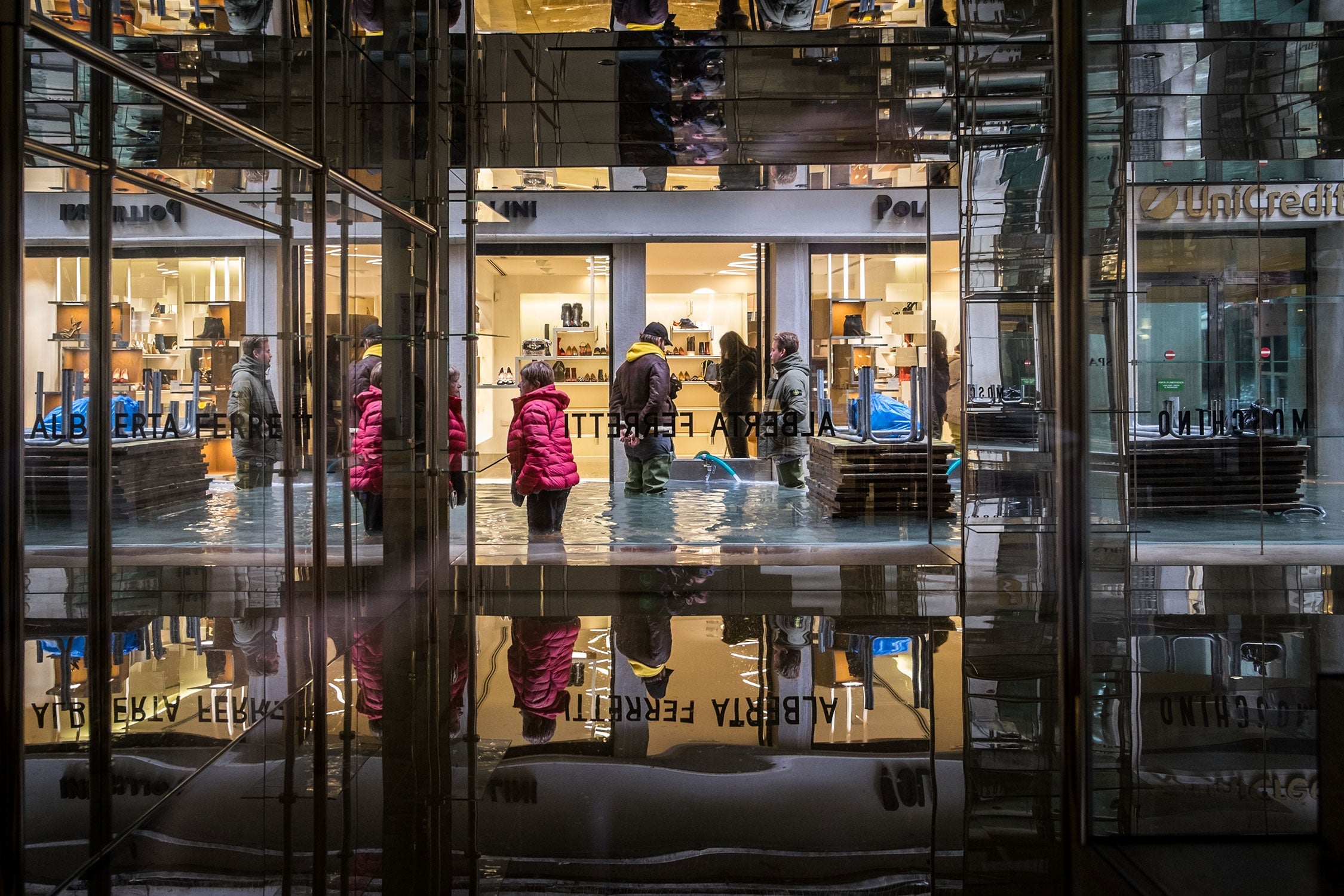 Tourists in front of shops, where owners are trying to pump out water.
