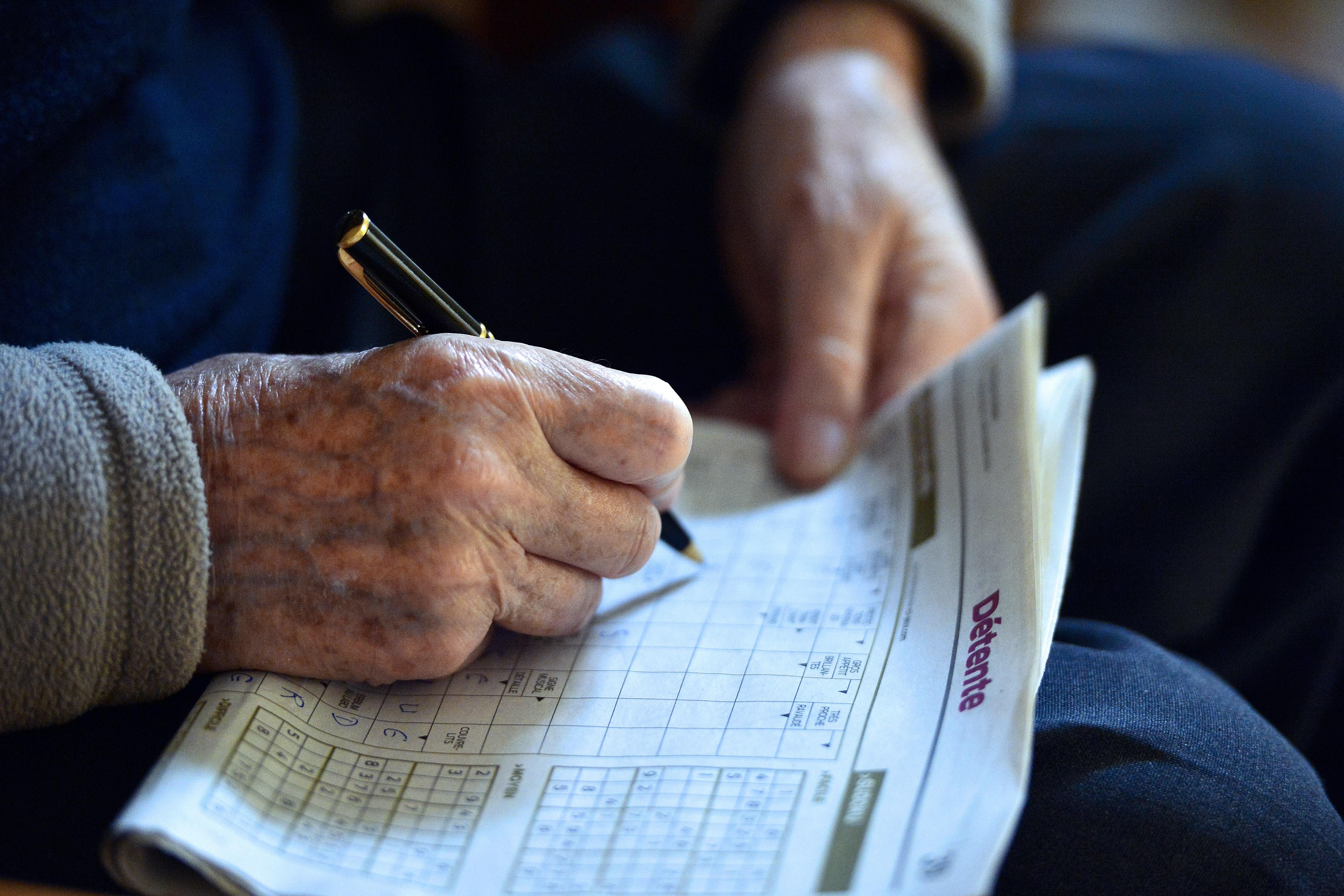 An elderly man fills in the crossword prior to Christmas eve dinner on December 24, 2014, at the St. Joseph retirement home in Nantes.