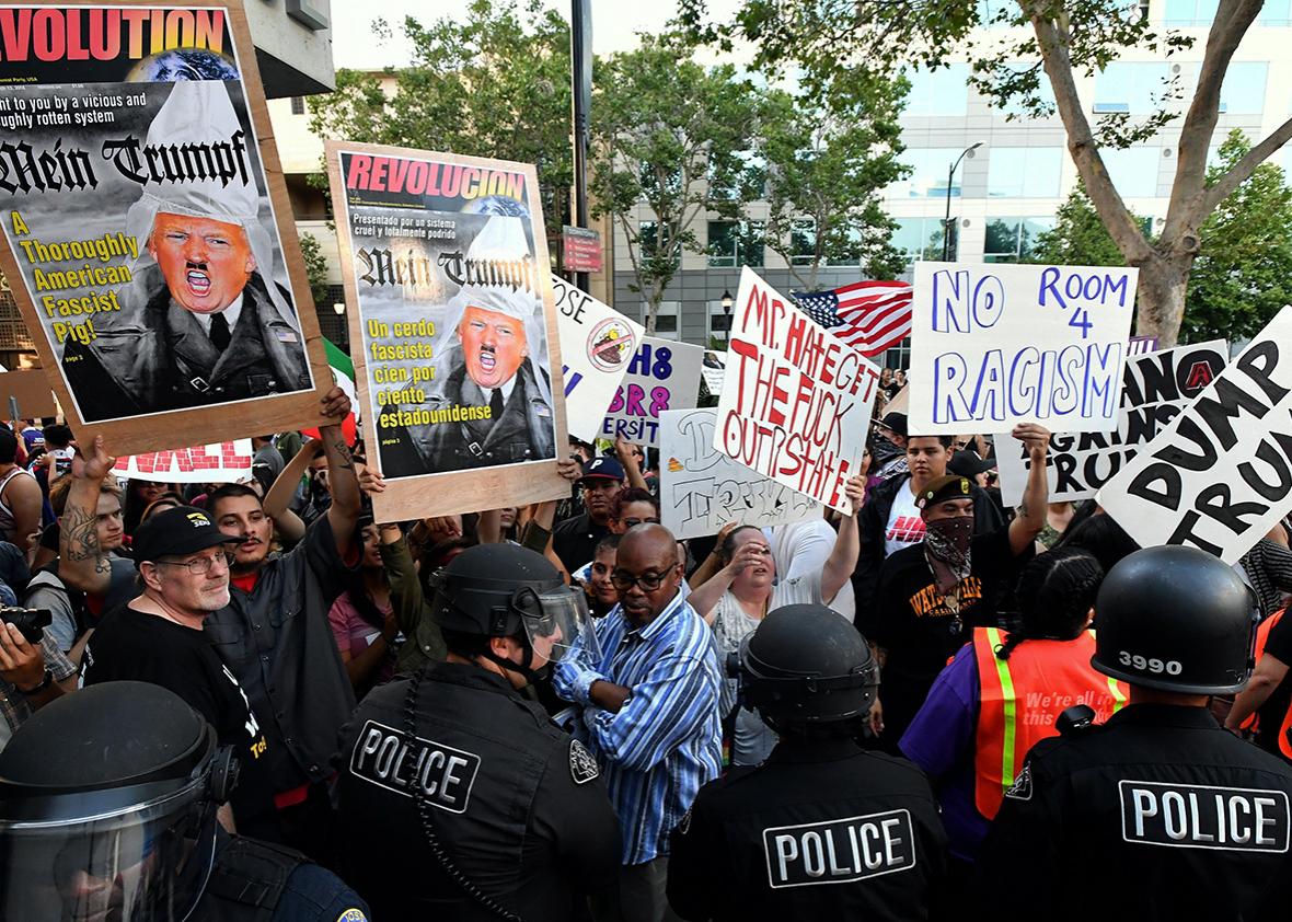 Protesters hold up signs against a police skirmish line near where Republican presidential candidate Donald Trump holds a rally in San Jose, California on June 02, 2016. 