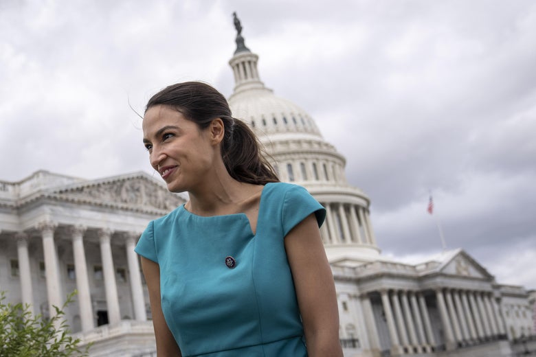 Ocasio-Cortez stands smiling outside the Capitol on a cloudy day