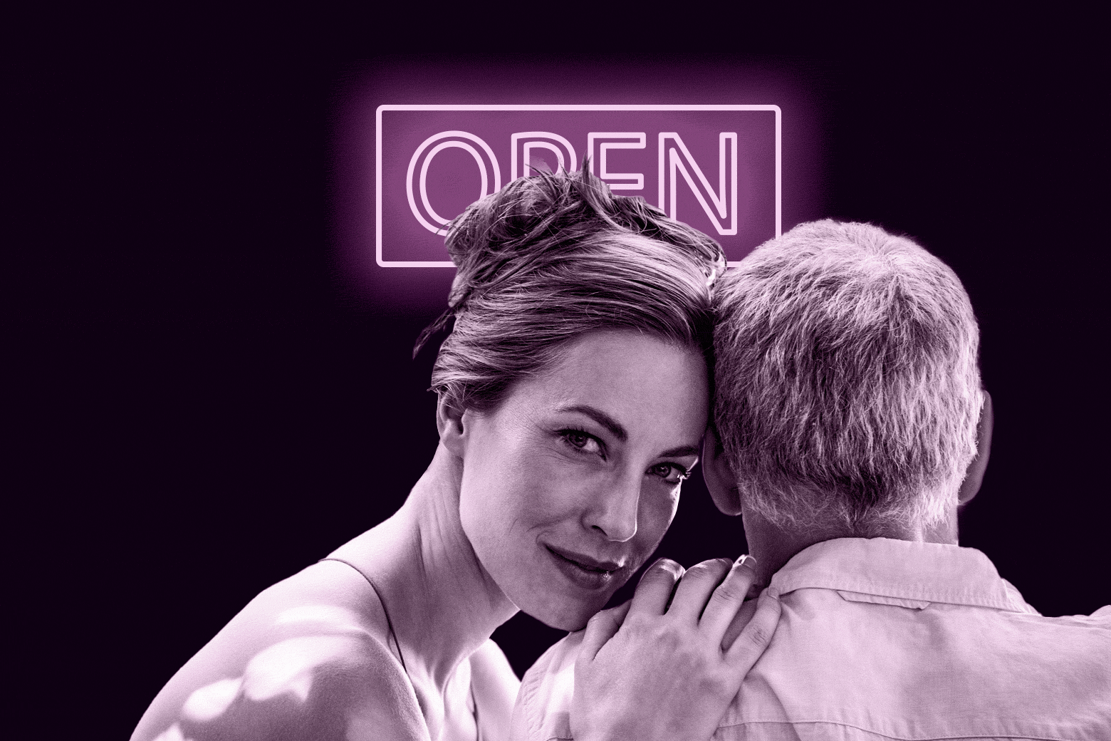 Woman and man holding each other in front of an open neon sign.