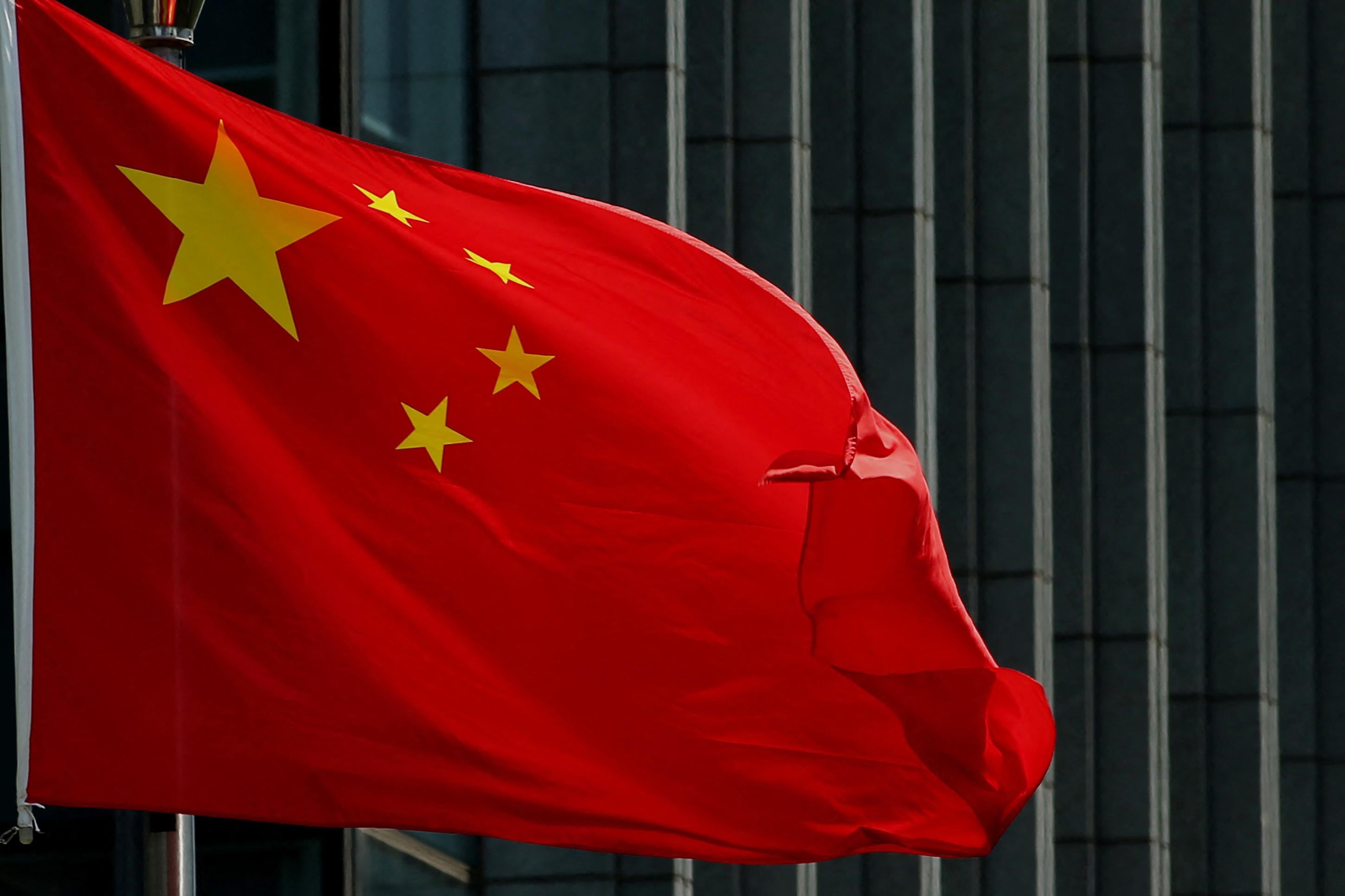 The Chinese flag flies in front of a building.