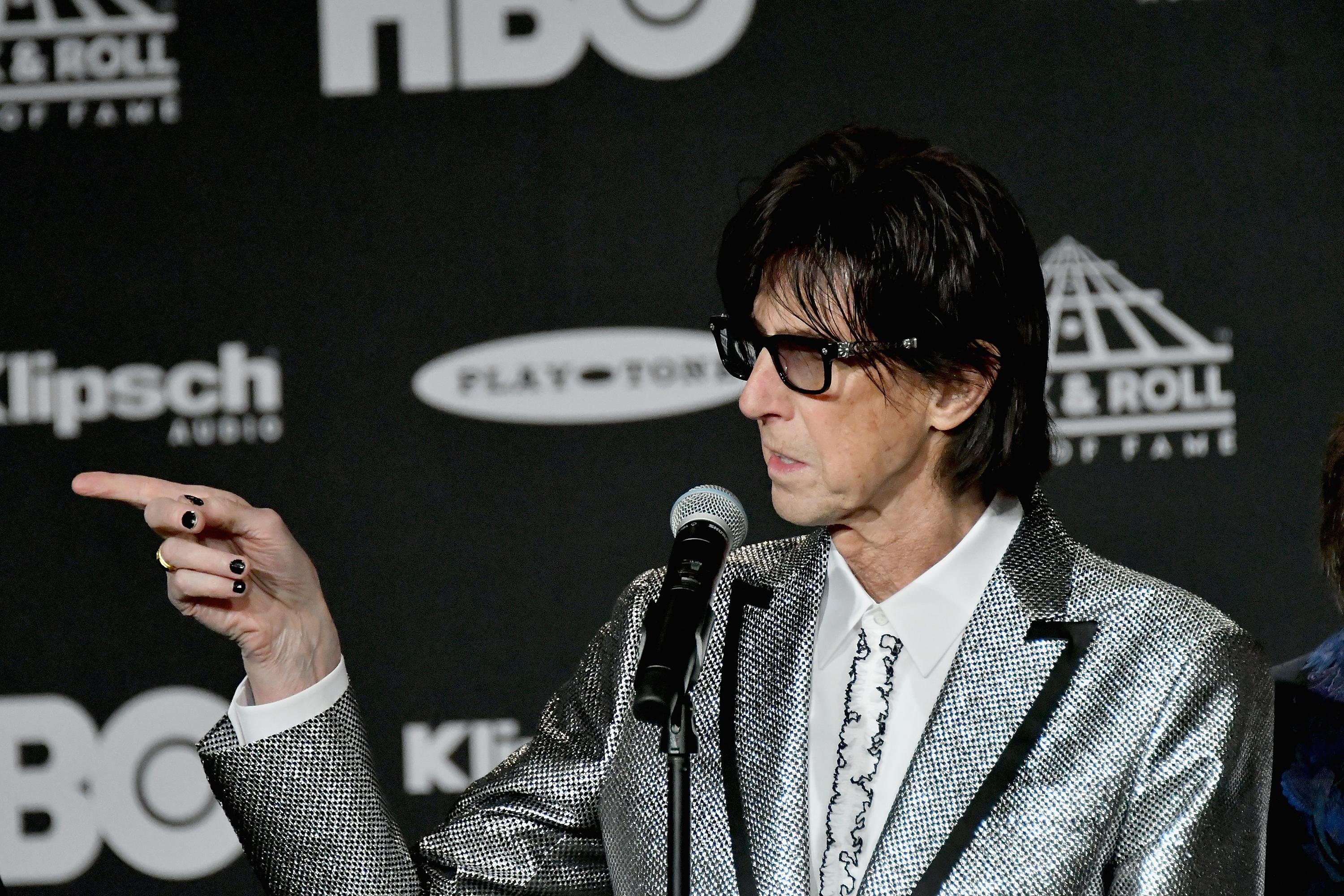 Ric Ocasek of the Cars points his finger at something off-camera at the Rock and Roll Hall of Fame.