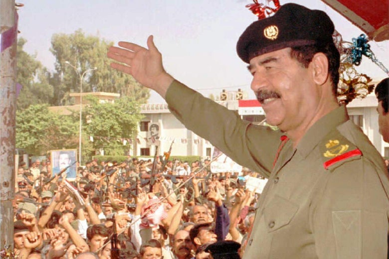 Saddam Hussein in military uniform and beret smiling and waving to a crowd of supporters in Baghdad, in 1995.