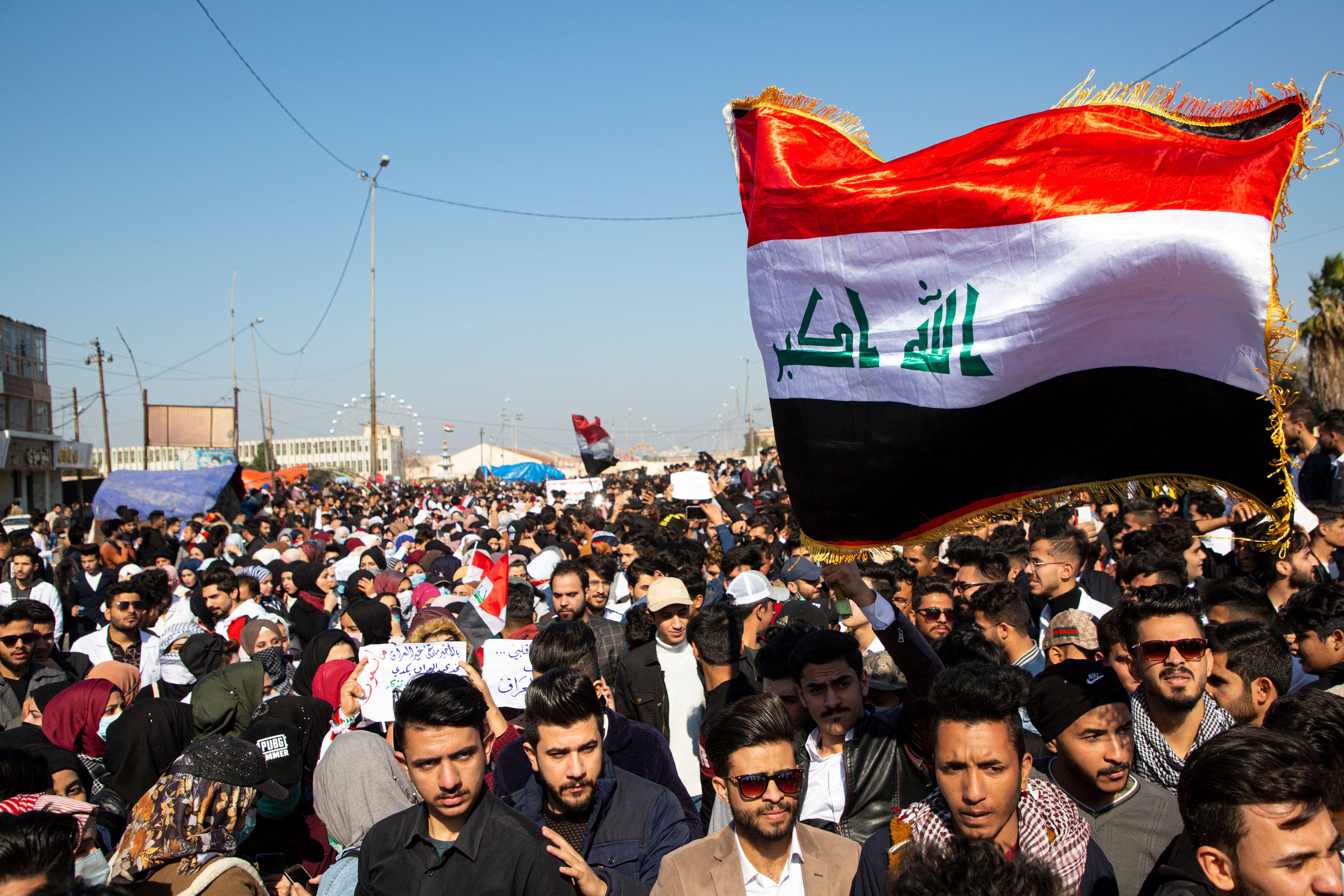 Iraqi demonstrators wave the national flag during an anti-government rally in the southern city of Basra.