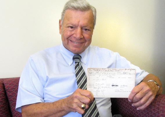 Peter Vallone holding the report card of his mother, Leah Palmigiano Vallone.