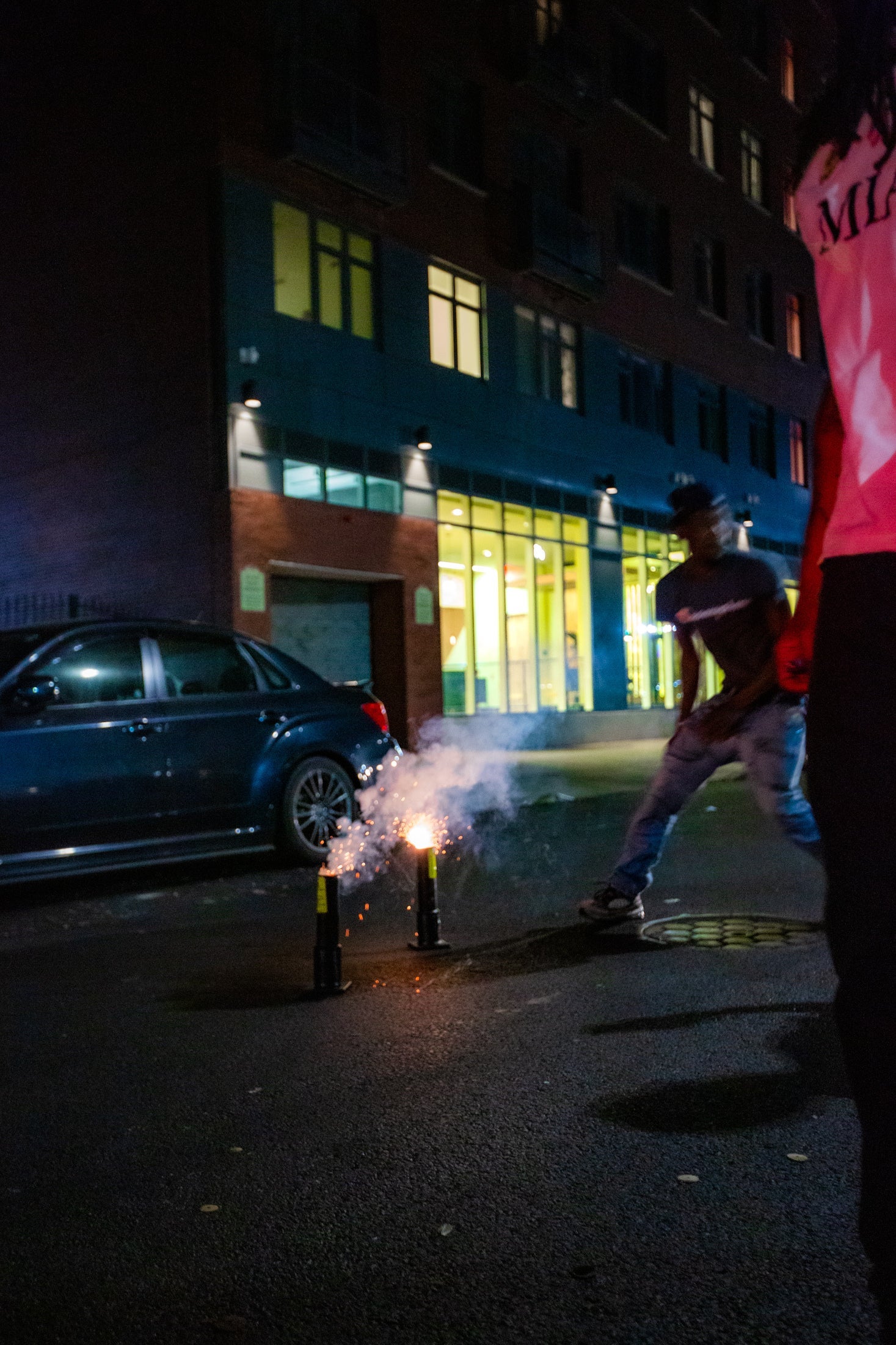 Men step back from lit fireworks in Brooklyn.