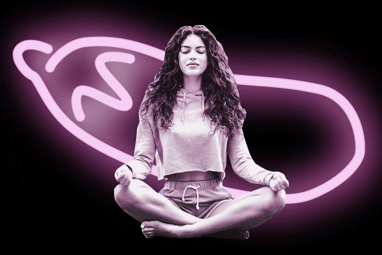Woman meditating in front of a glowing neon eggplant.
