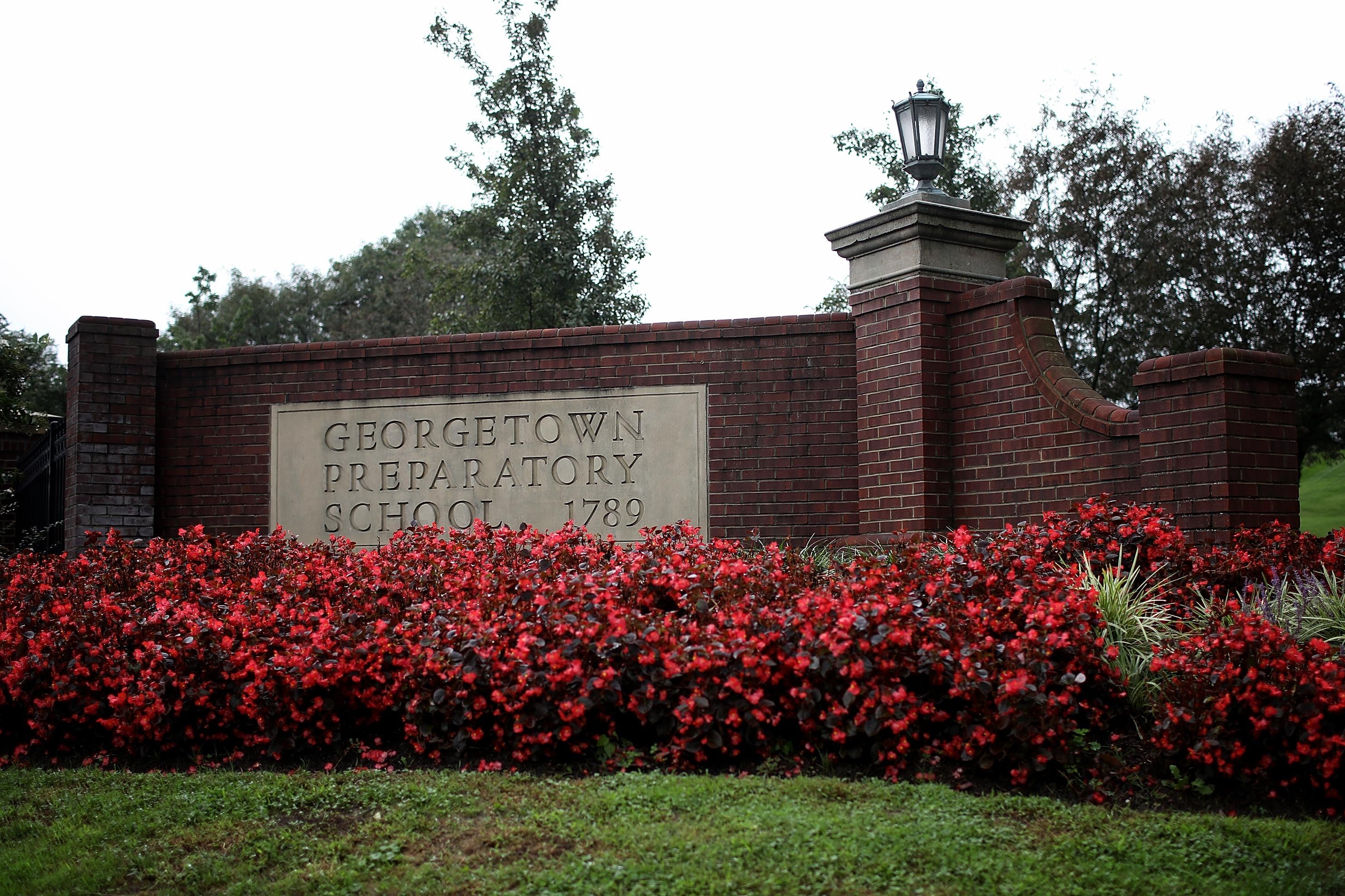 A sign for the Georgetown Preparatory School surrounded by red flowers. 