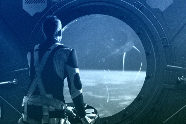 A person in a spacesuit looks out of a window of a spaceship into space.