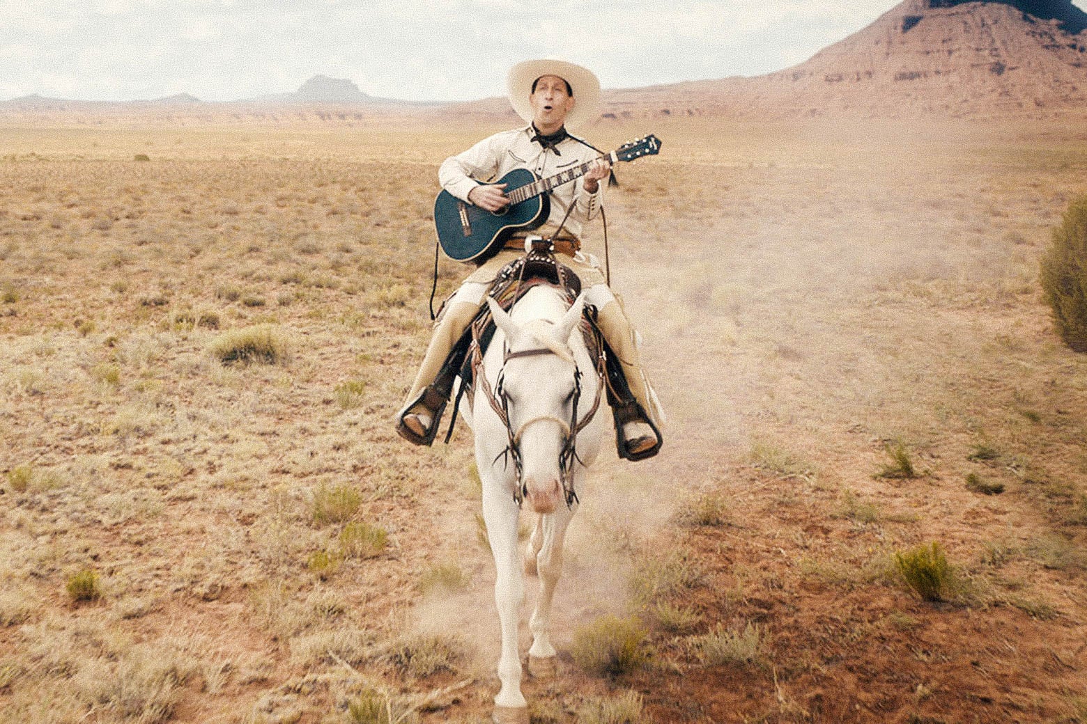 Tim Blake Nelson riding a horse and playing the guitar in this still from The Ballad of Buster Scruggs.