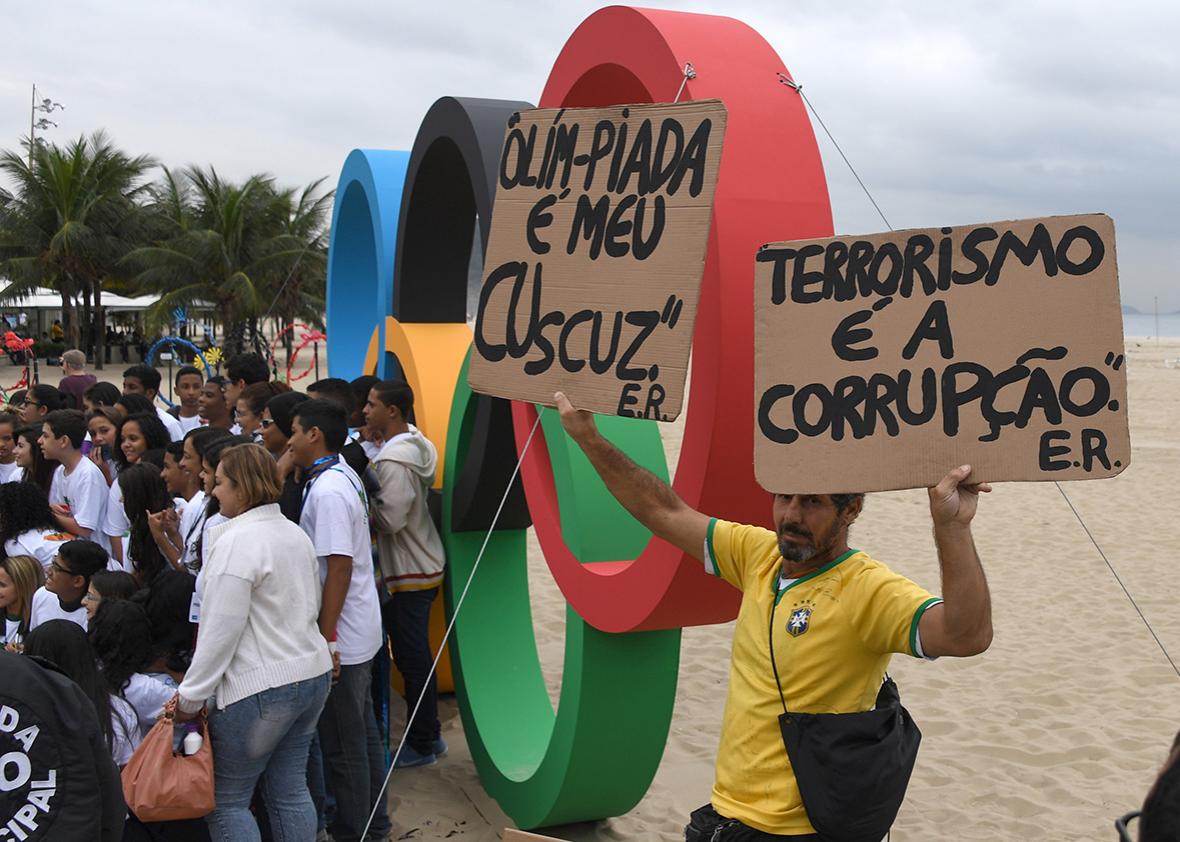 Activists protest against corruption in front of Olympic rings made out of recycled material inaugurated in Copacabana Beach on July 21, 2016.