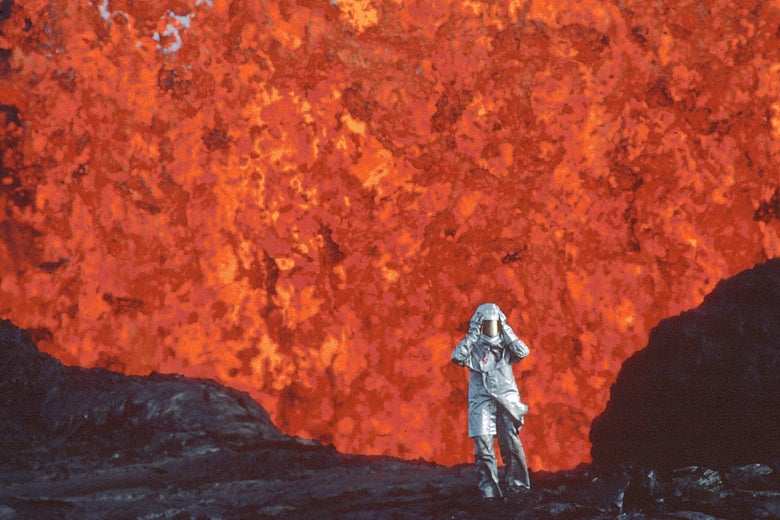 A woman walking in front of lava, wearing an aluminum suit.
