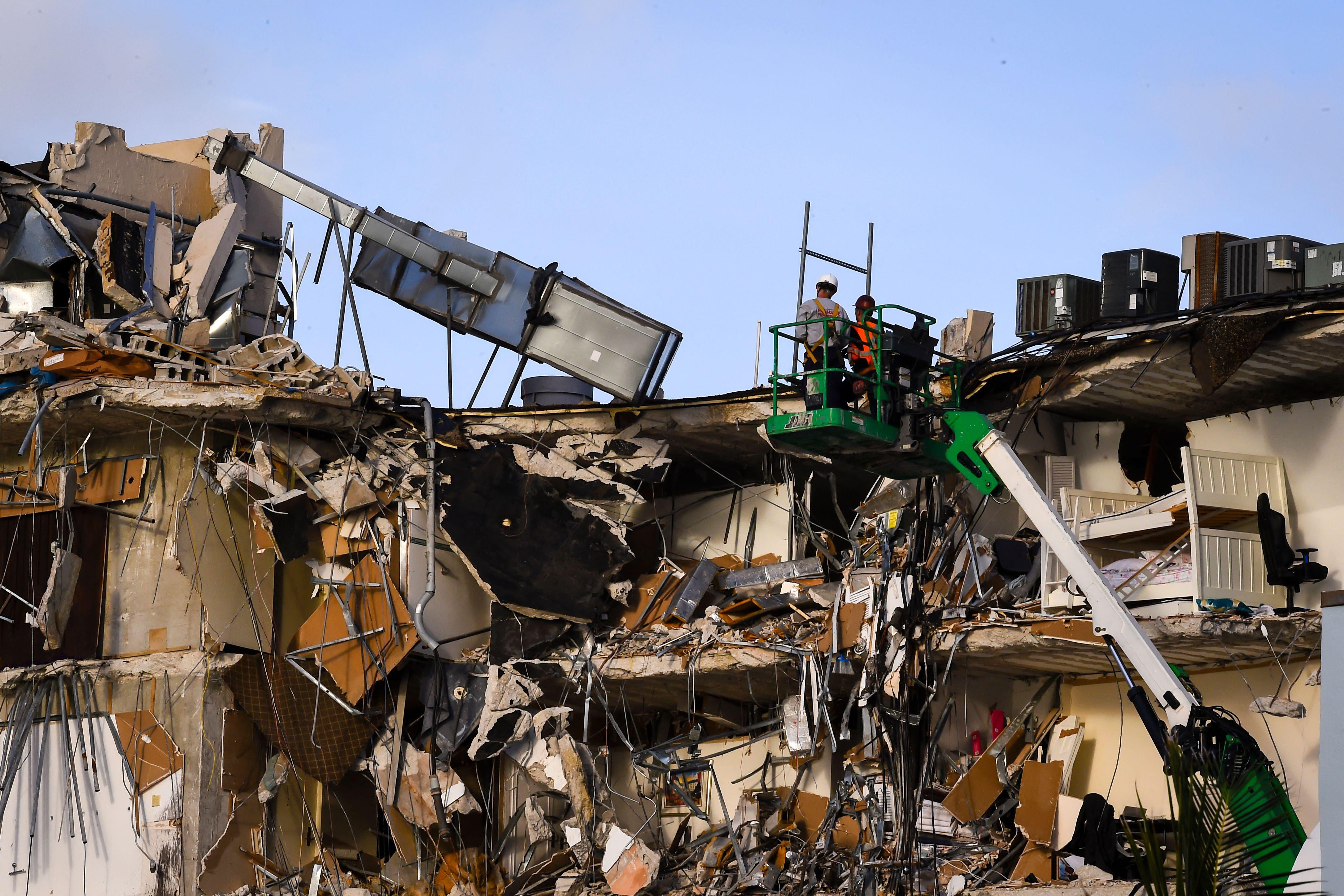 Rescue workers on a green crane stand above the wreckage of a partially collapsed building in Surfside north of Miami Beach, Florida.