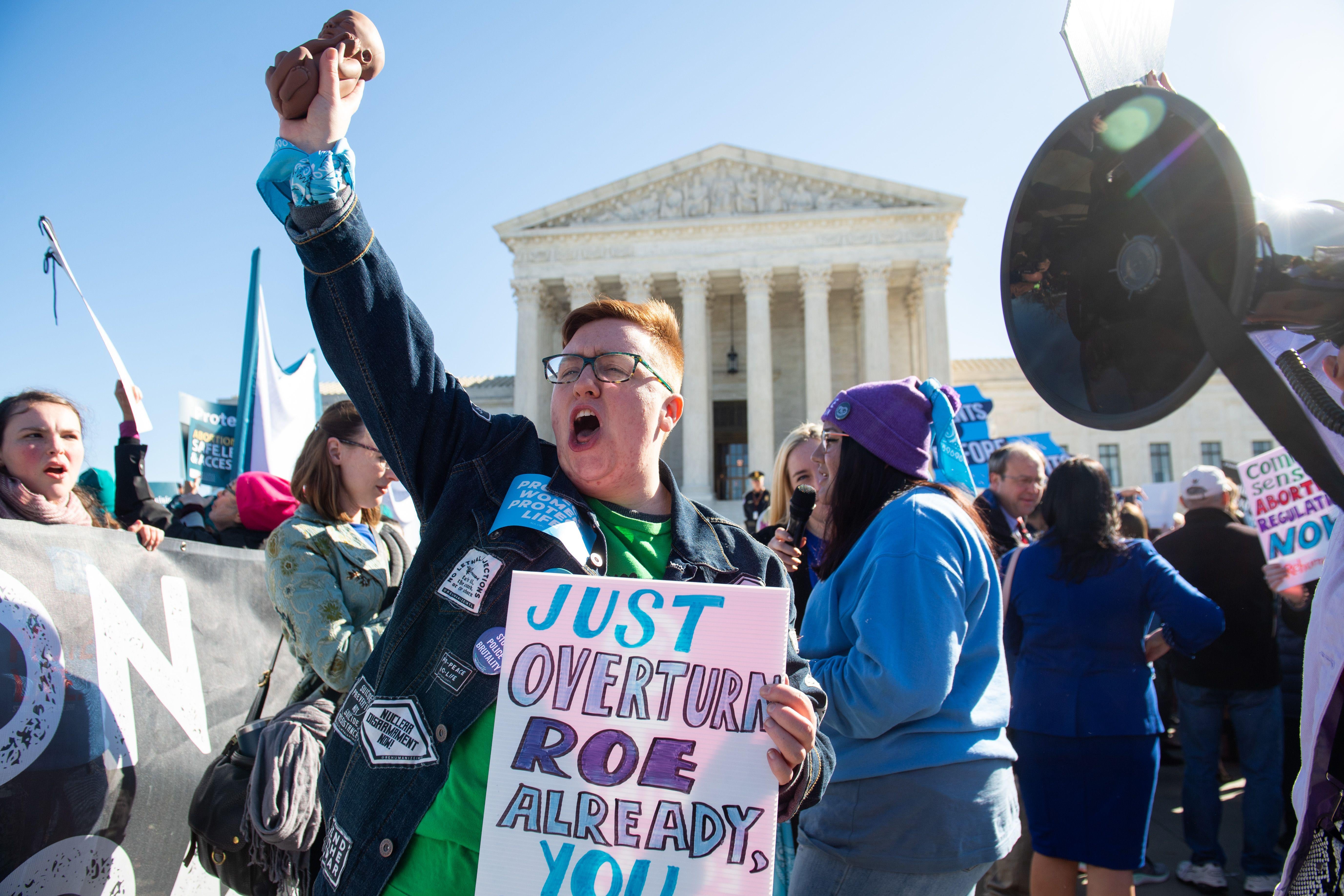 A protester holding a sign urging the Supreme Court to overturn Roe v. Wade.