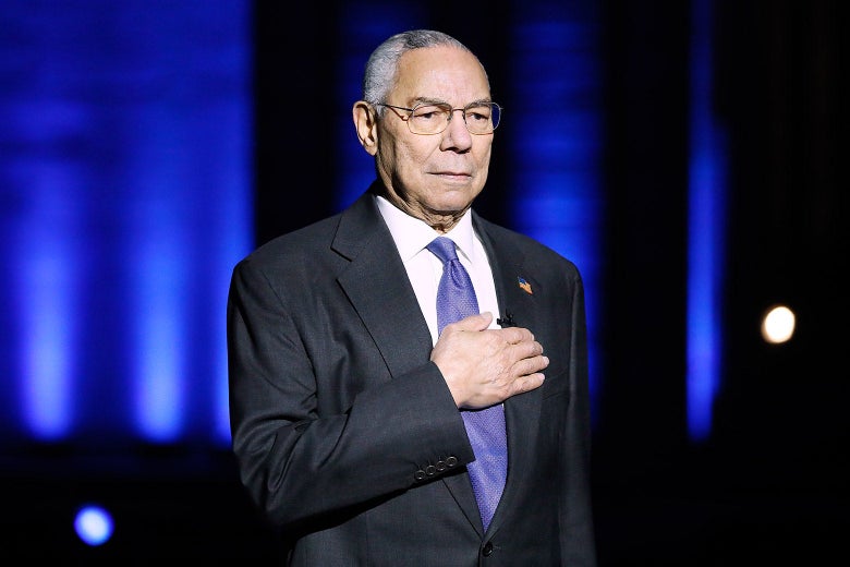 Colin Powell stands with his right hand over his heart onstage at a Memorial Day concert