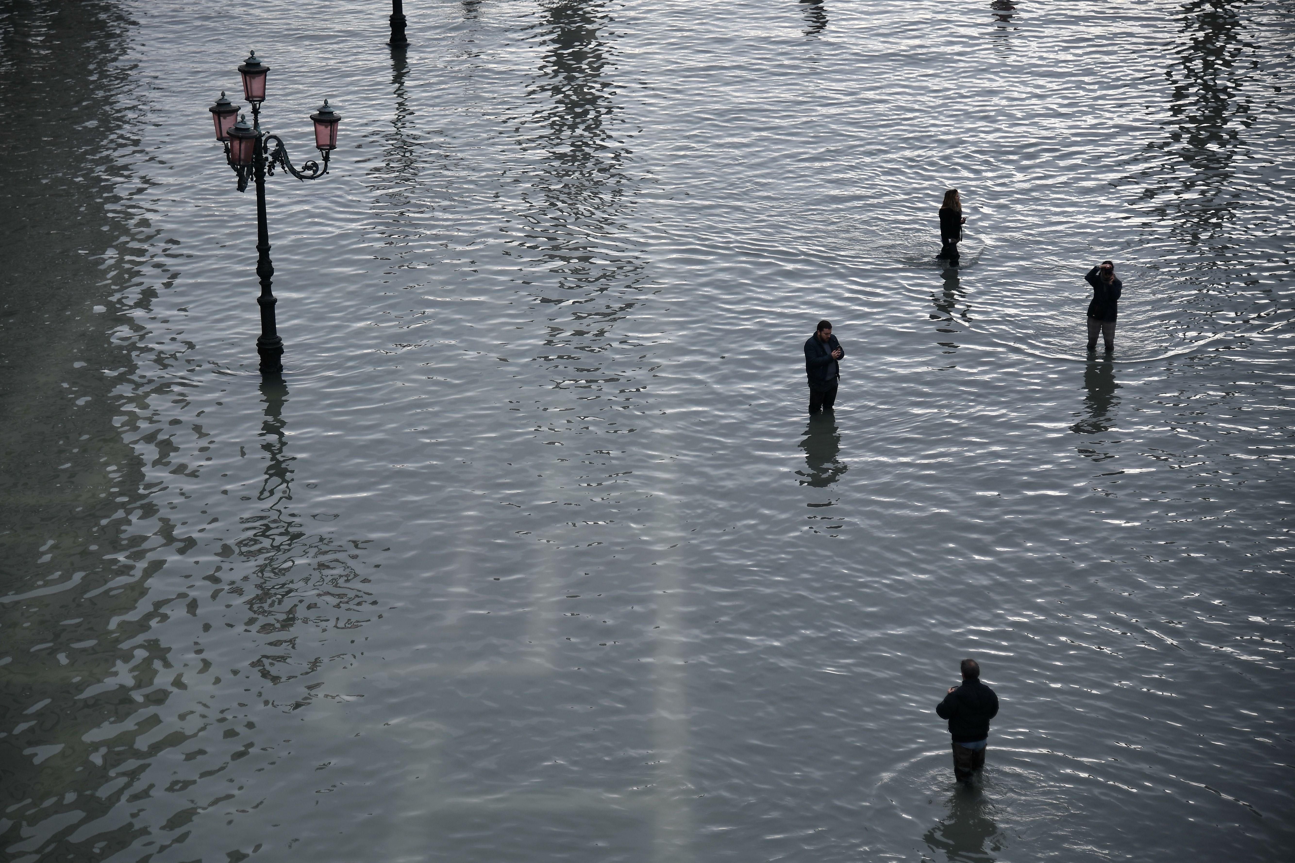 People take photos at the flooded St. Mark's Square.