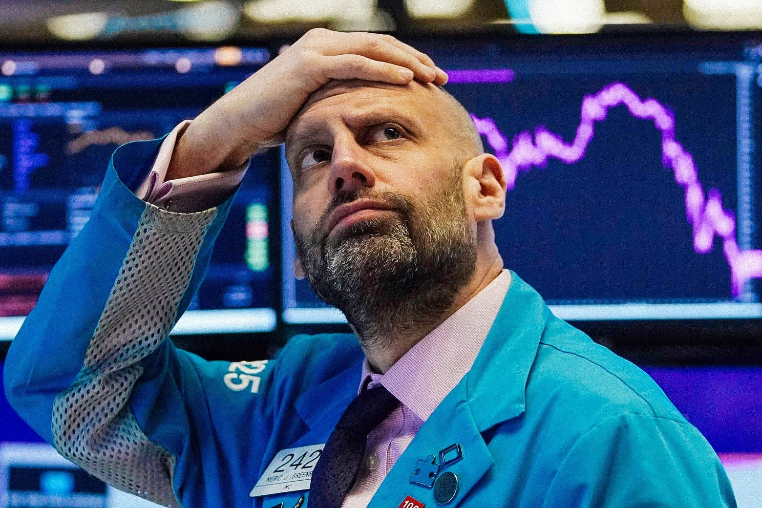 Meric Greenbaum puts his hand on his head in dismay, looking up at the board at the New York Stock Exchange on Monday.