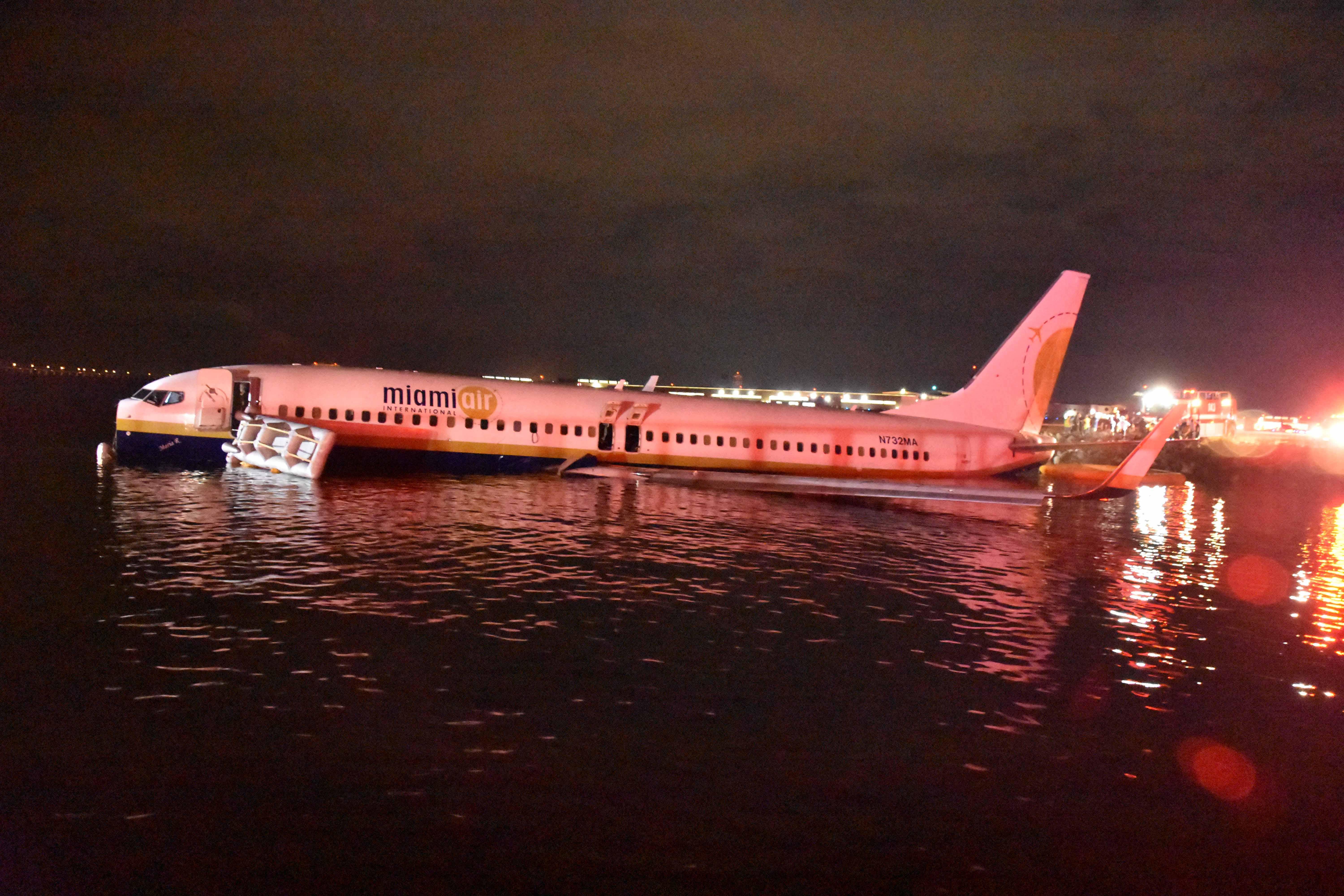 The plane resting on the water, lit by red emergency lights.