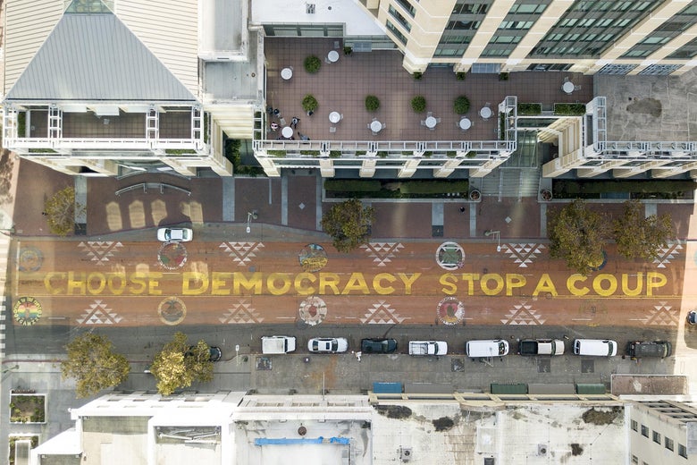 An aerial view of a mural on a street that reads “Choose Democracy Stop a Coup.”