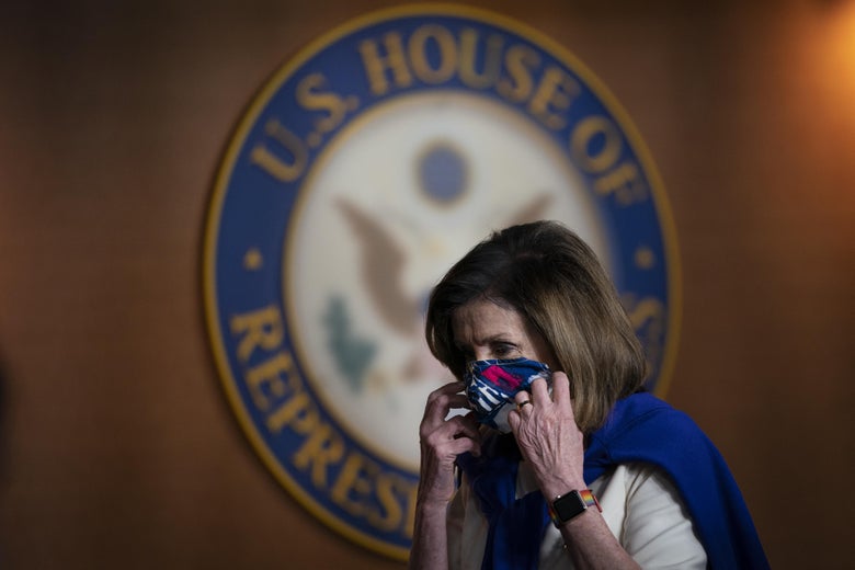 Nancy Pelosi puts on a mask in front of a U.S. House of Representatives sign.
