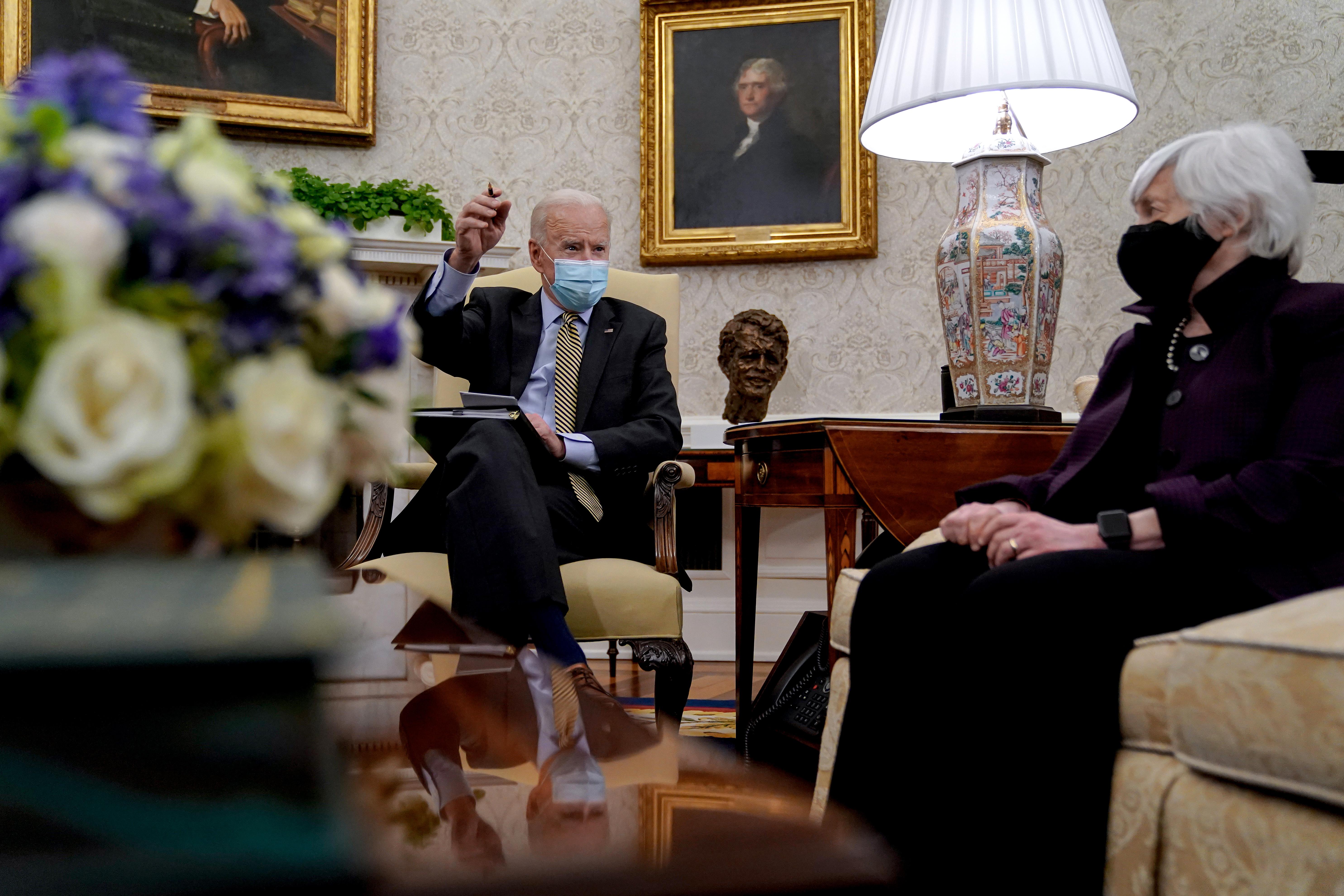 Joe Biden sits with Janet Yellen in the Oval Office, both wearing masks