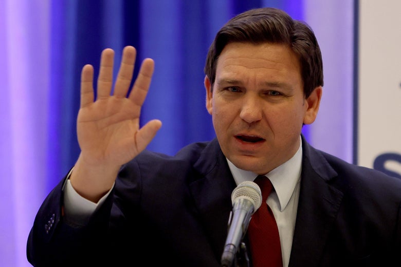 Ron DeSantis holds up his hand, looking annoyed.