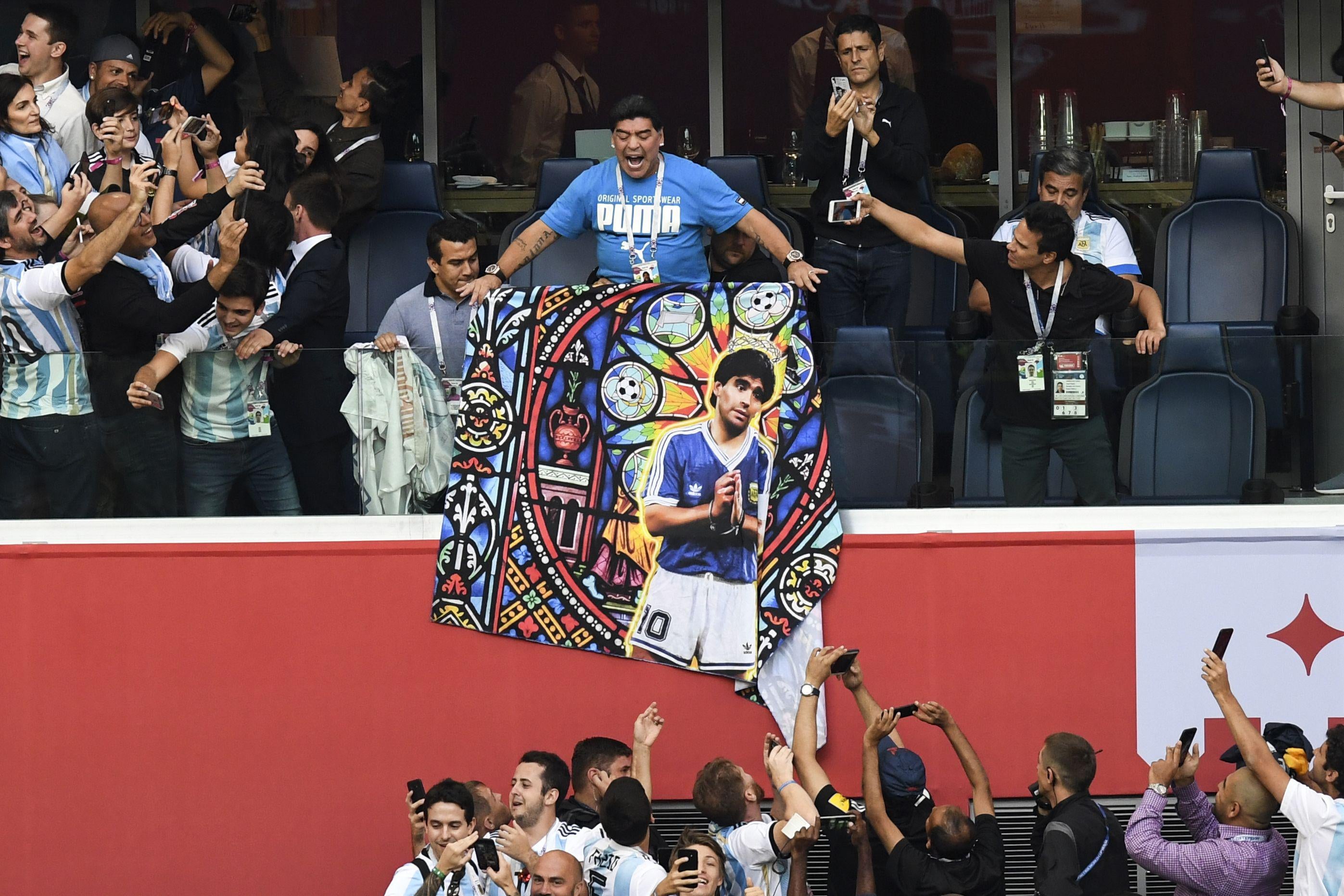 Retired Argentina forward Diego Maradona carries a poster bearing his portrait ahead of the Russia 2018 World Cup Group D football match between Nigeria and Argentina at the Saint Petersburg Stadium in Saint Petersburg on June 26, 2018. (Photo by Paul ELLIS / AFP) / RESTRICTED TO EDITORIAL USE - NO MOBILE PUSH ALERTS/DOWNLOADS (Photo credit should read PAUL ELLIS/AFP/Getty Images)