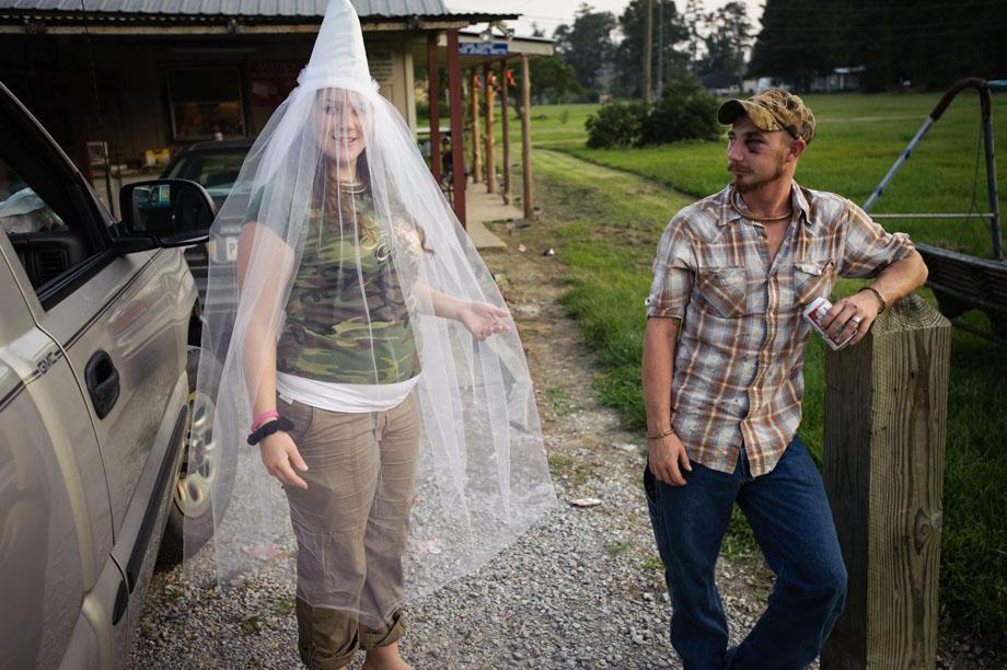 “Little Charlie” of the Dixie Rangers of the Ku Klux Klan displays her custom made wedding veil, as her fiancée watches on.