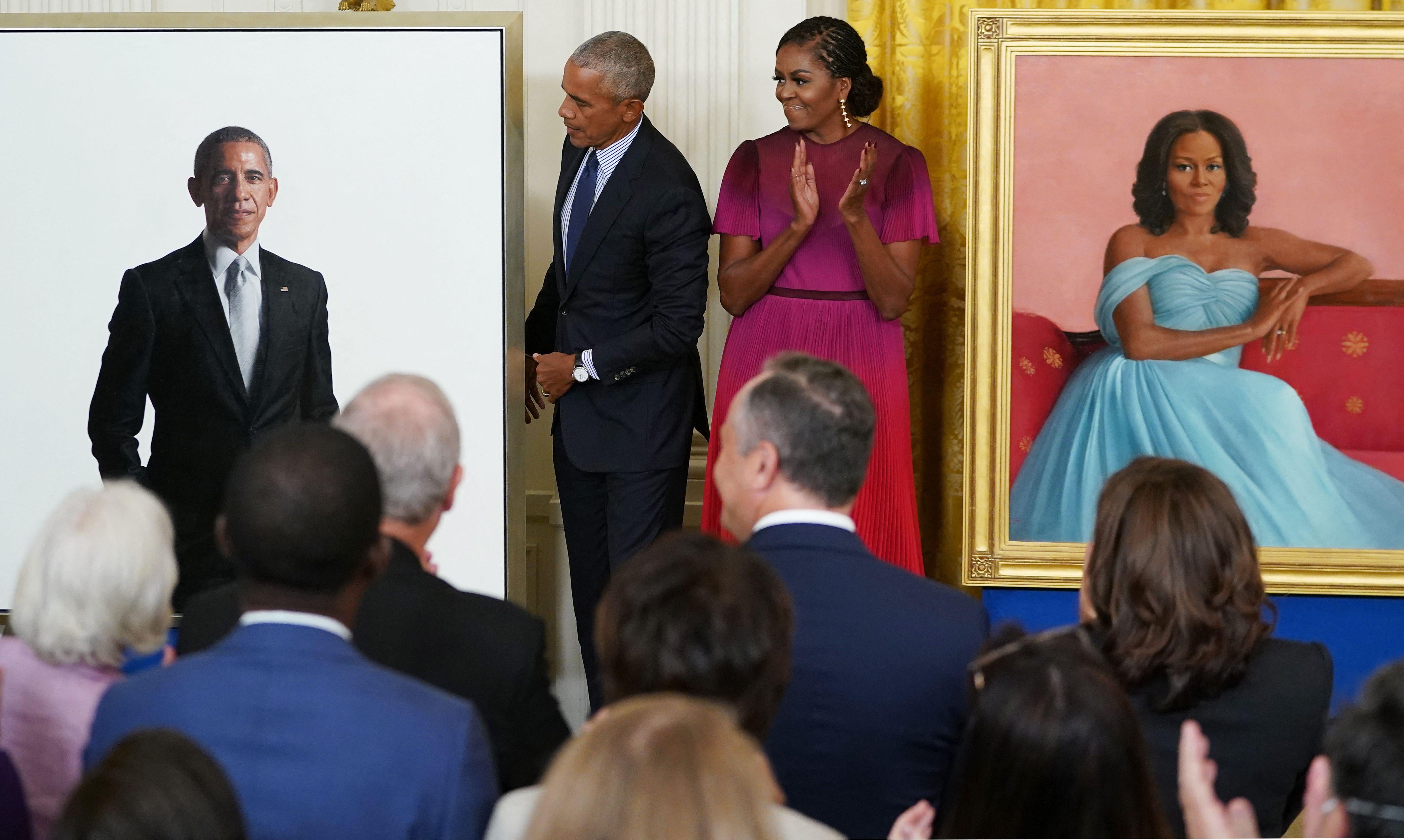 Barack Obama and Michelle Obama look at Barack Obama's official White House portrait, a photorealistic painting on a white background.