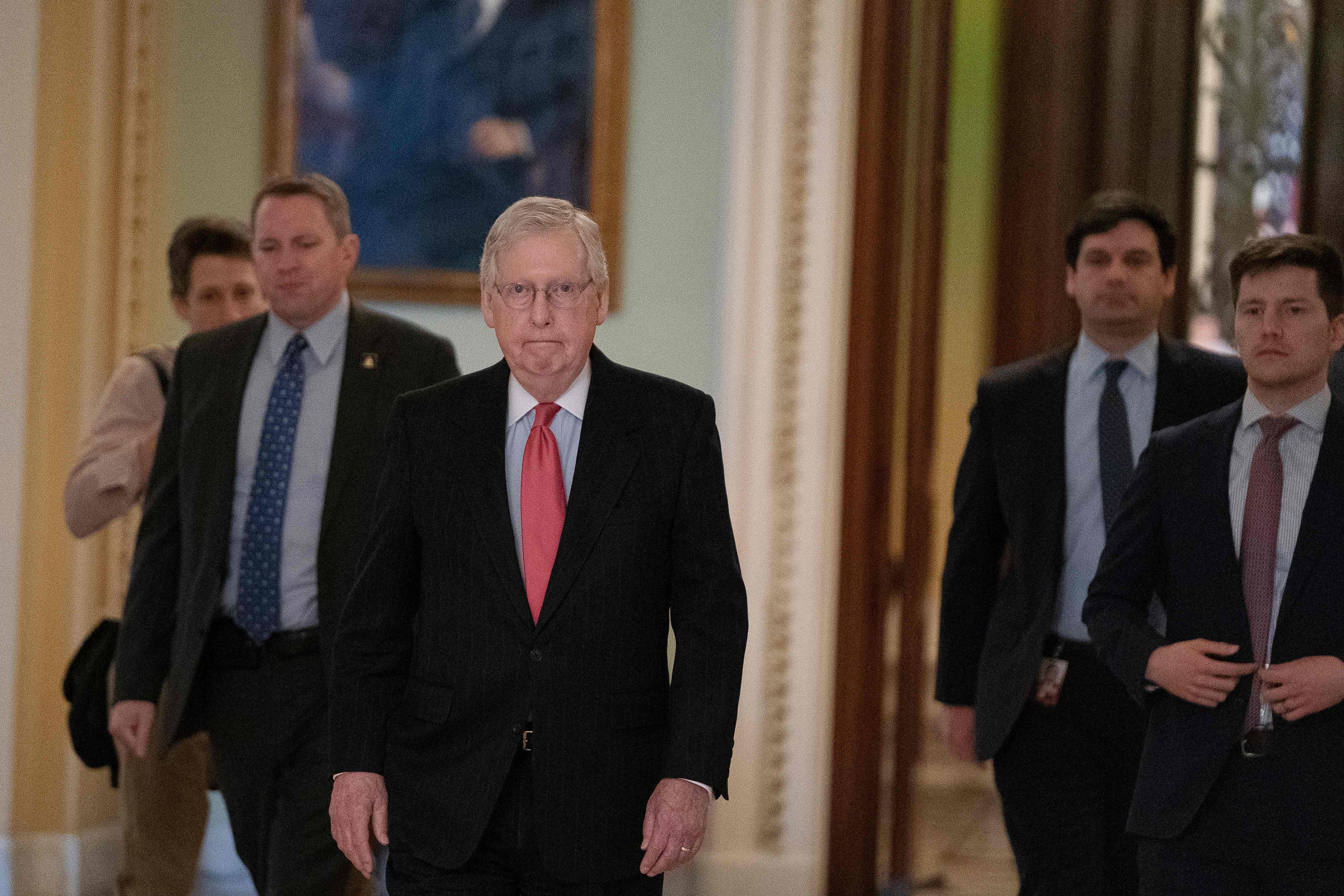 Mitch McConnell walking through the halls of Congress with other men around him