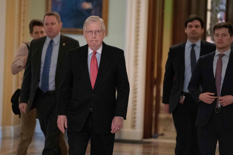Mitch McConnell walking through the halls of Congress with other men around him
