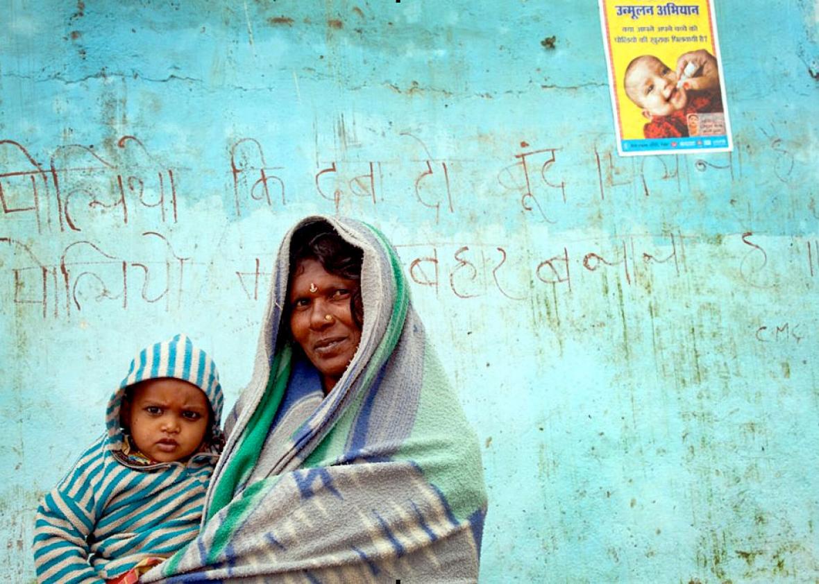 A mother and child pose in front of a polio eradication slogan a