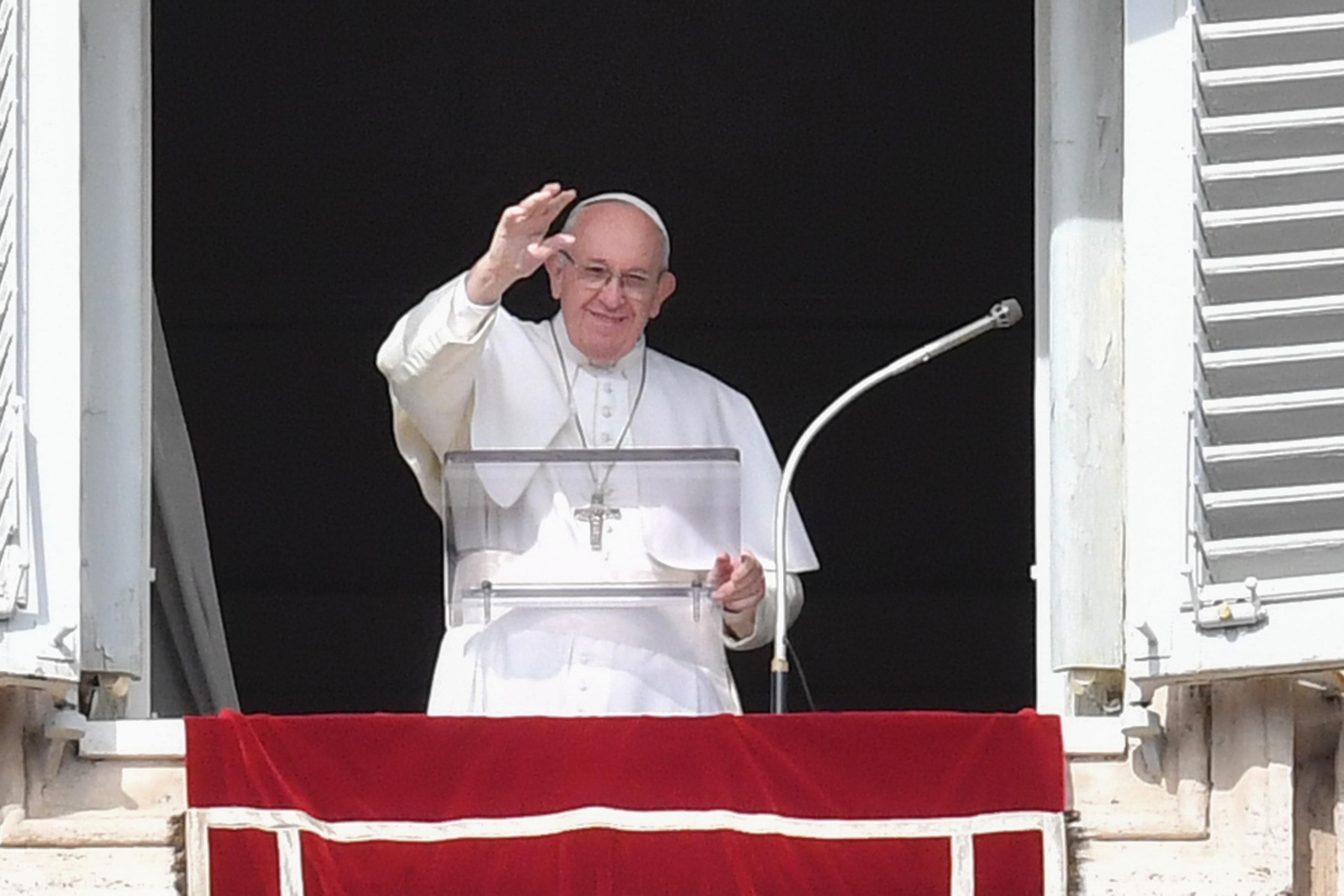 Pope Francis waves from his window of the Apostolic Palace overlooking St. Peter's square.