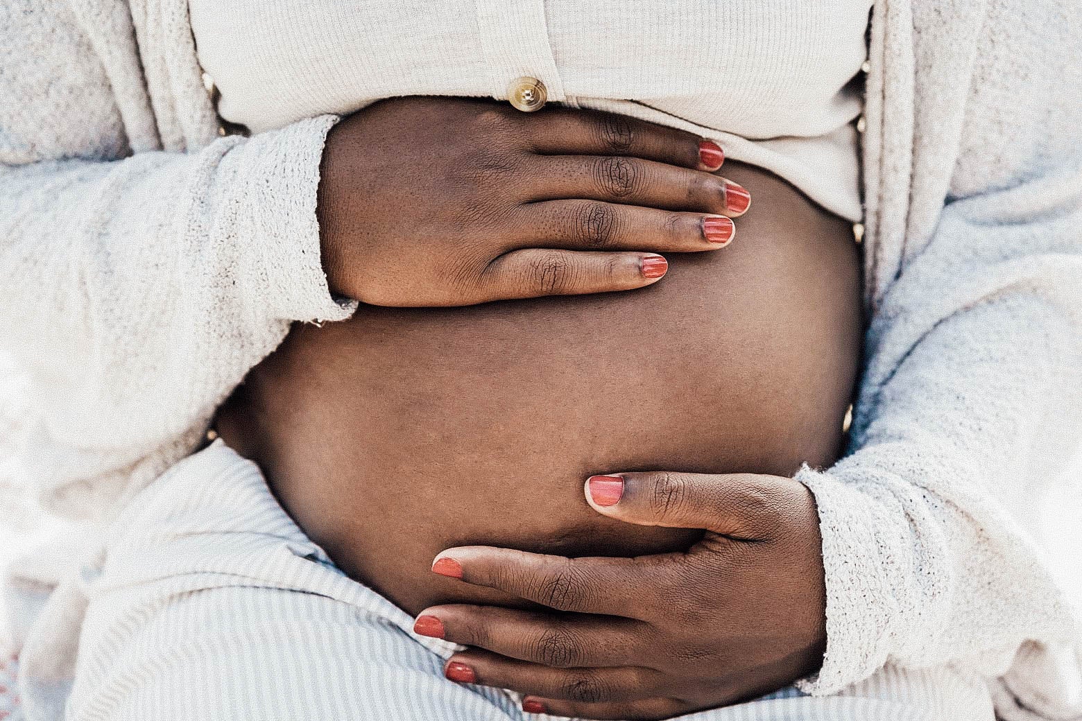Image of a pregnant Black woman holding her belly. 