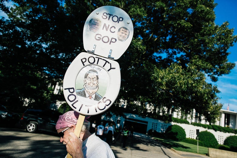 A man wearing a bandanna carries a sign protesting North Carolina's House Bill 2.