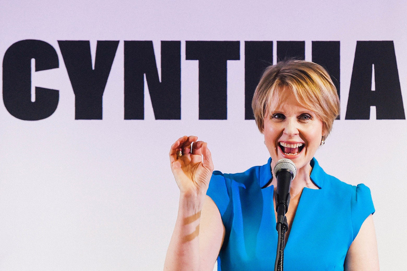 Cynthia Nixon standing in front of a campaign sign that says Cynthia.